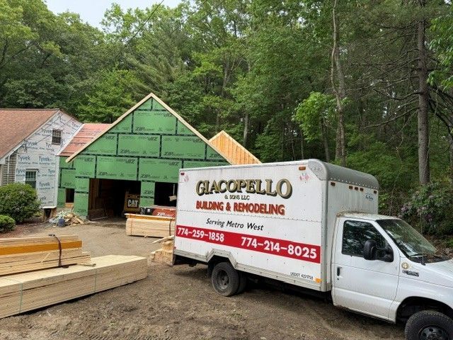 Truck with “GLACOPELLO BUILDING & REMODELING” sign parked at a house under construction with green siding.