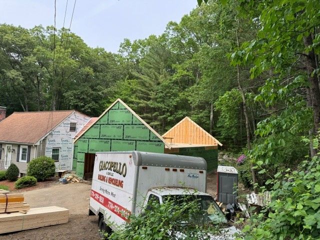 White house and green-roofed buildings beside a moving truck in a wooded driveway