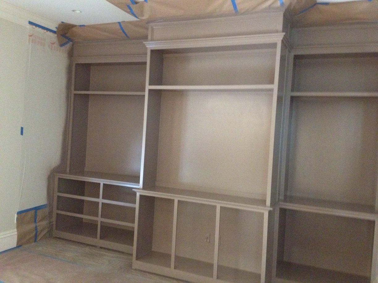 Three unfinished wooden built-in shelves against a light wall, covered in tape.