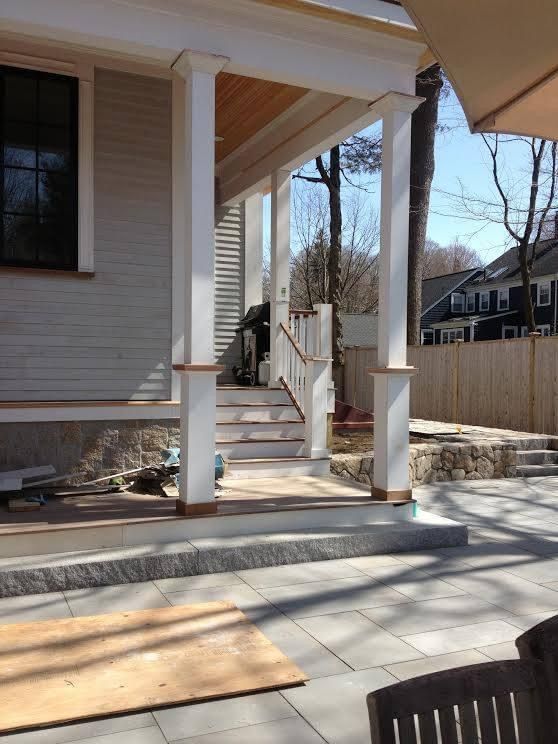 Exterior porch with white columns, steps, and gray patio.