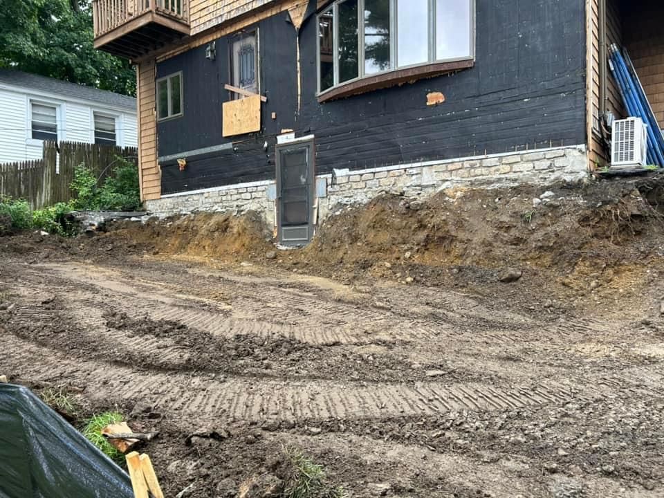 Dirt excavation near a house with a damaged exterior and a side door.