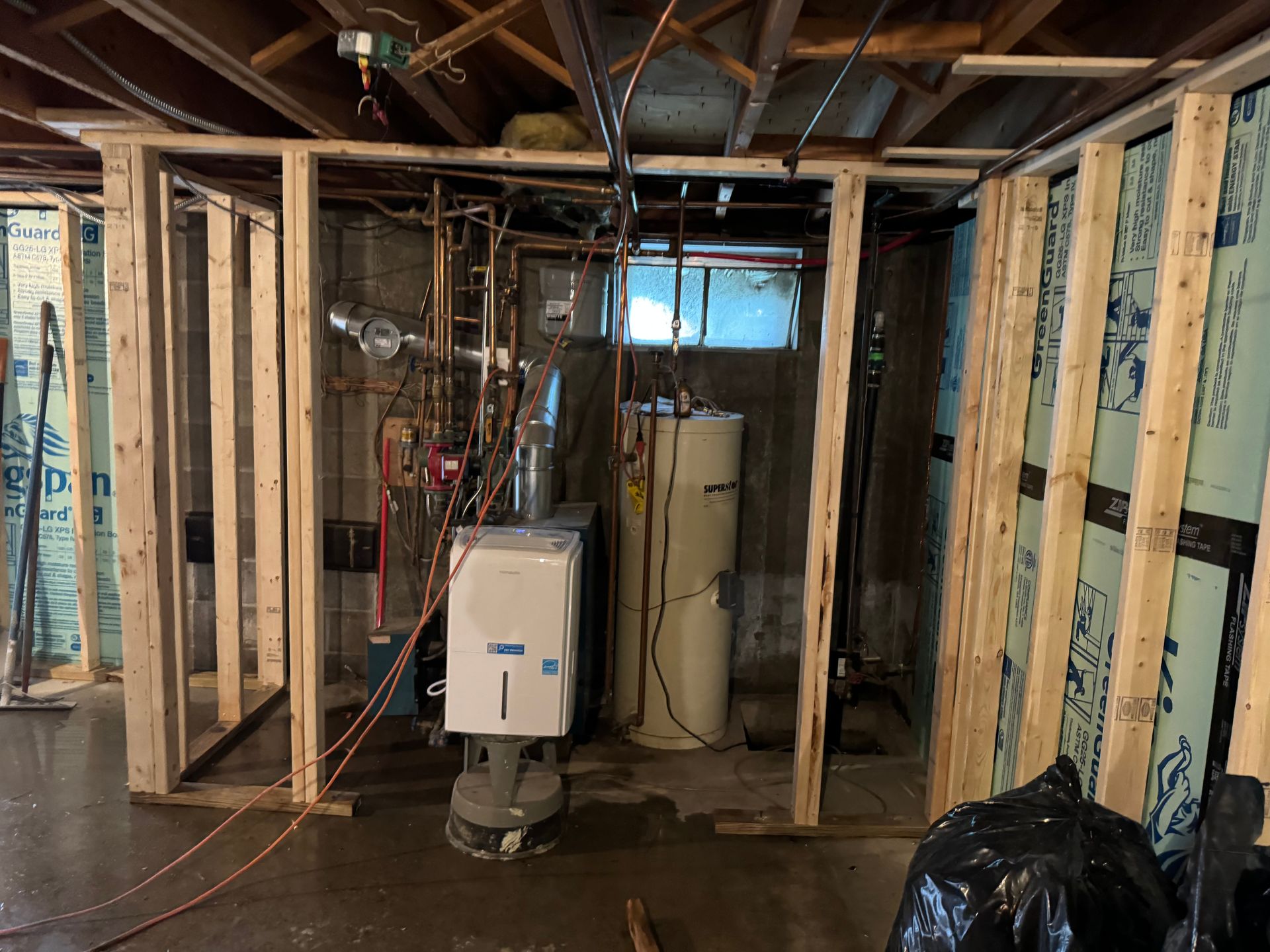 Basement with unfinished wood framing around mechanical equipment; a water heater and furnace are visible.