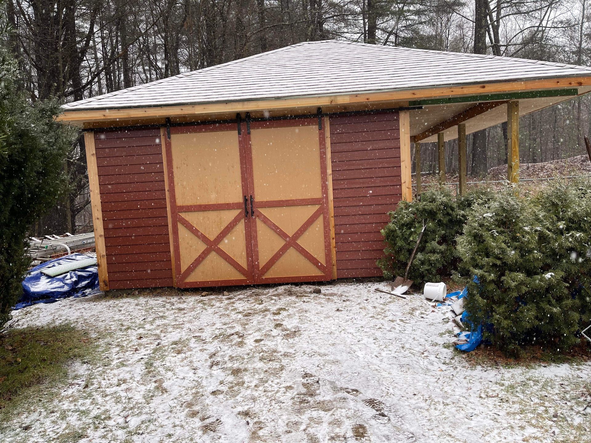 Brown and tan shed with a snow-covered roof and ground.