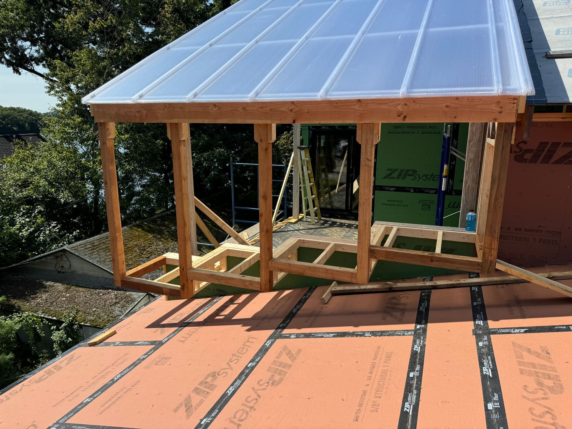 Wooden structure with clear plastic roof panels being built on a rooftop.