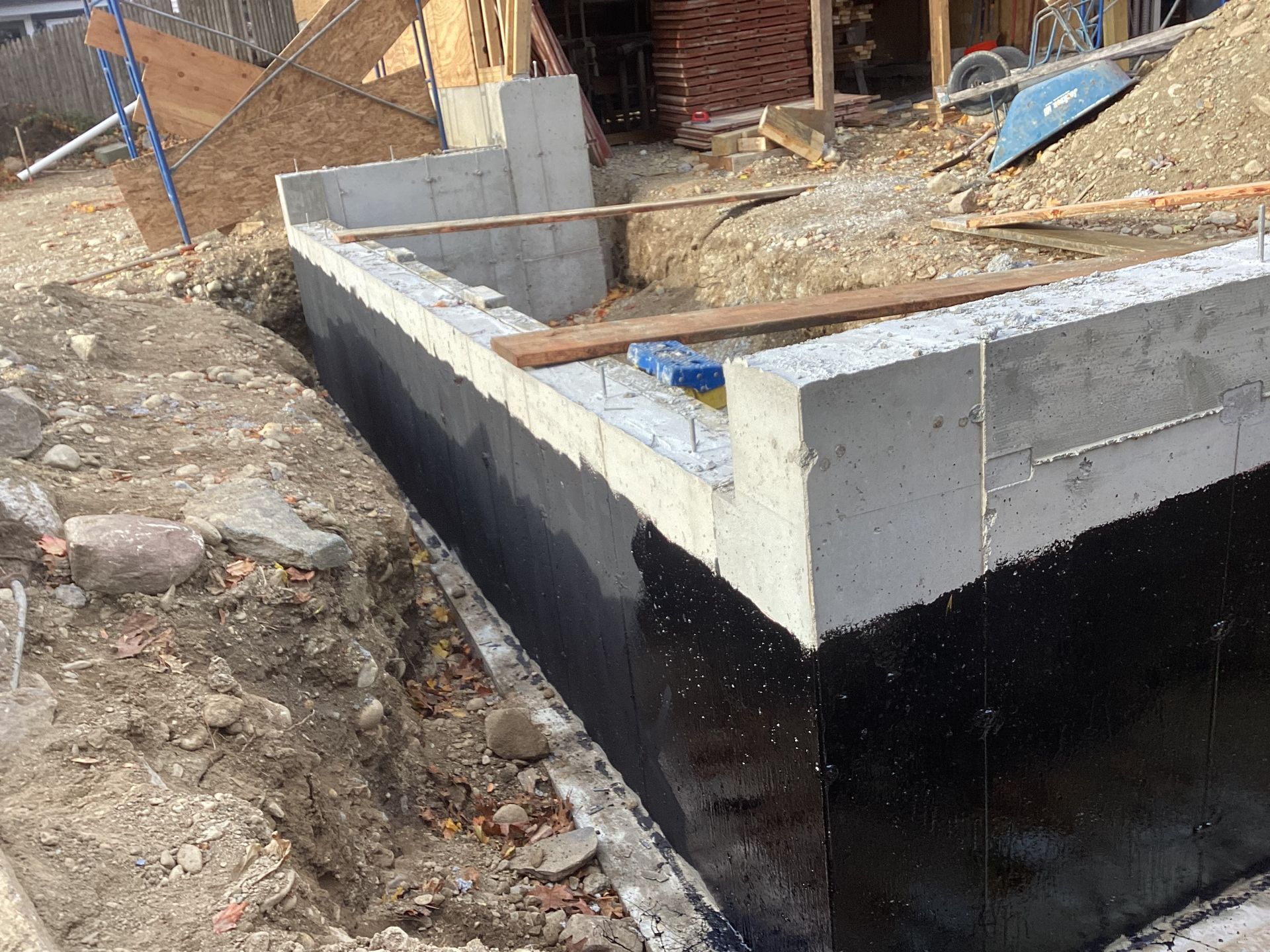 Foundation wall construction with black waterproofing membrane.