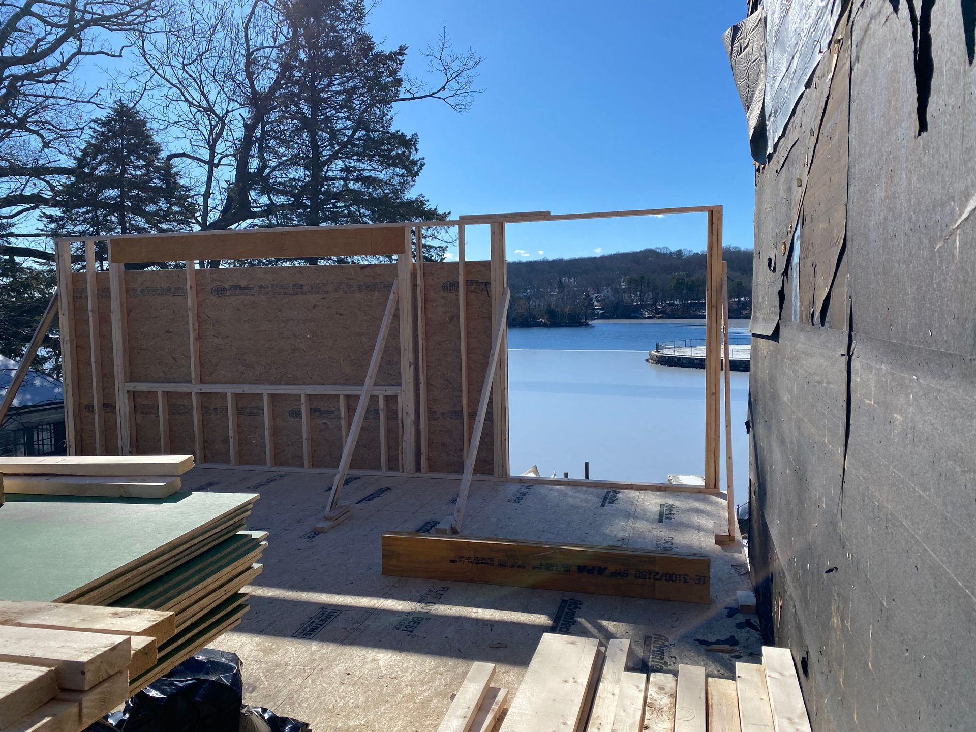 Construction of a building frame with a lake view in the background. Wood framing is visible.