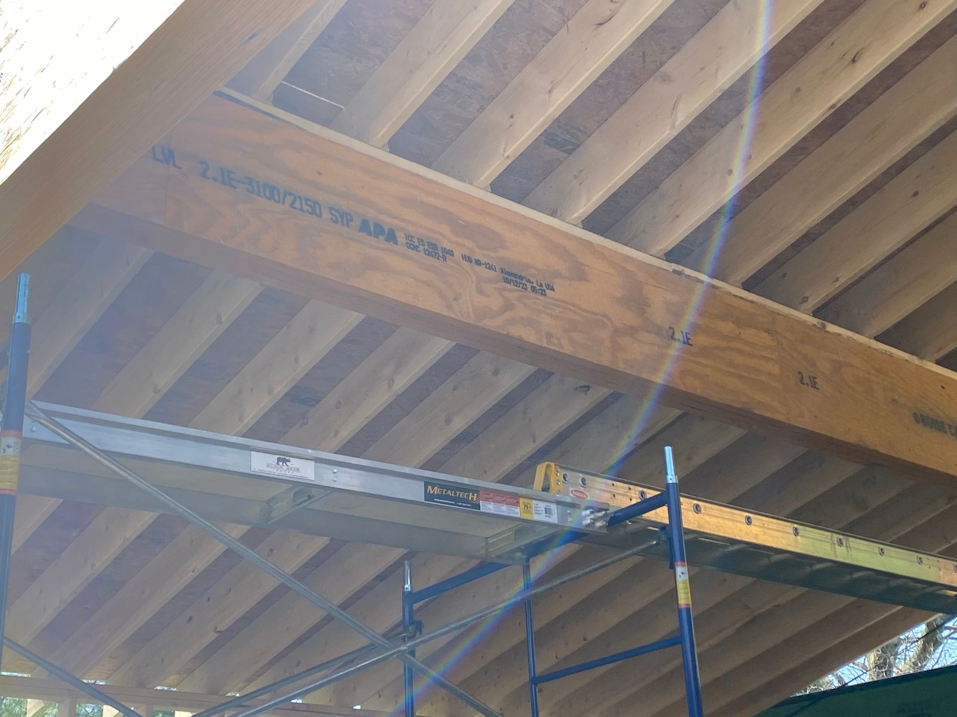 Wooden roof structure under construction, viewed from below with scaffolding.