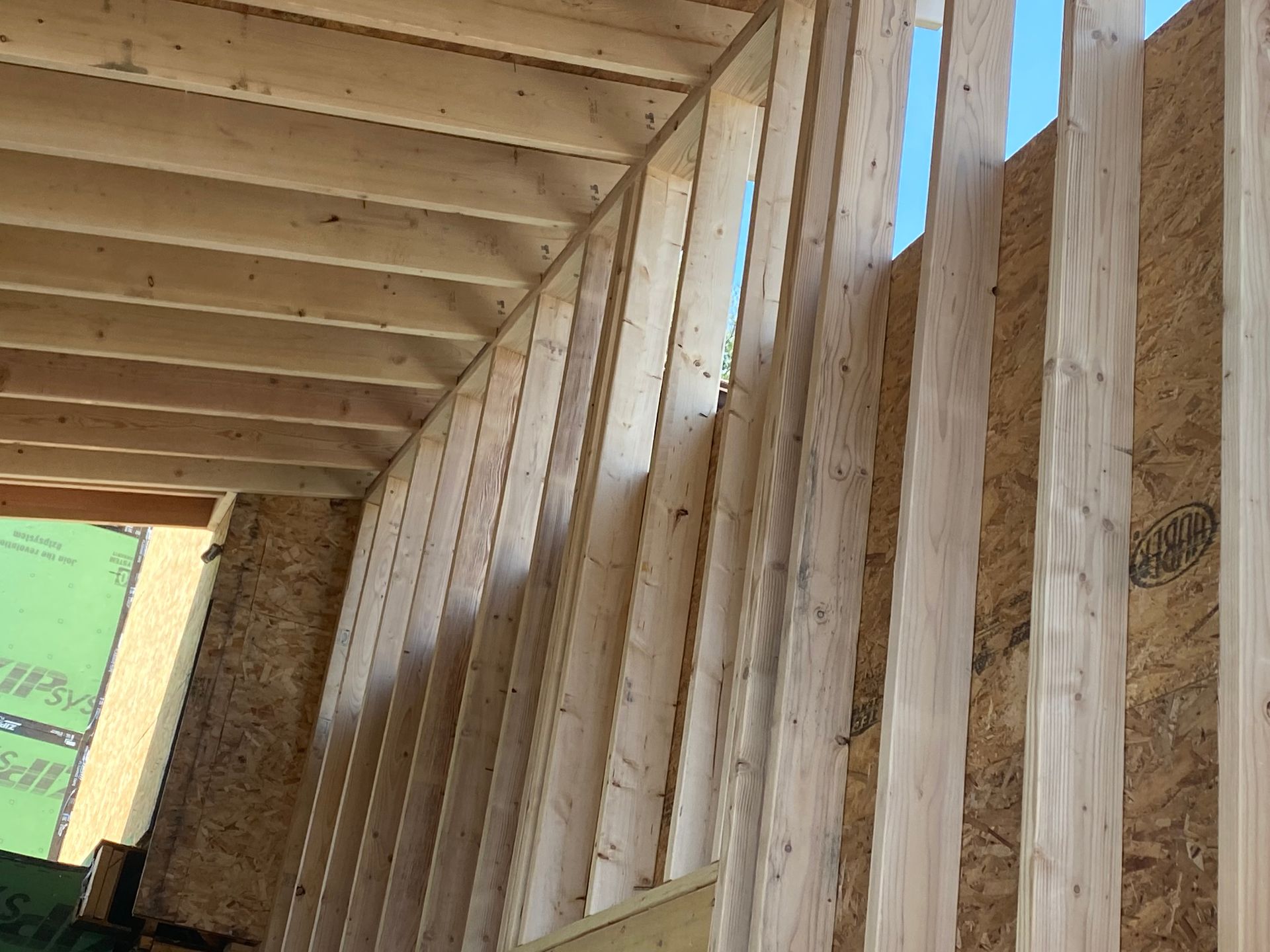 Wooden framing of a building under construction, with exposed studs and rafters.