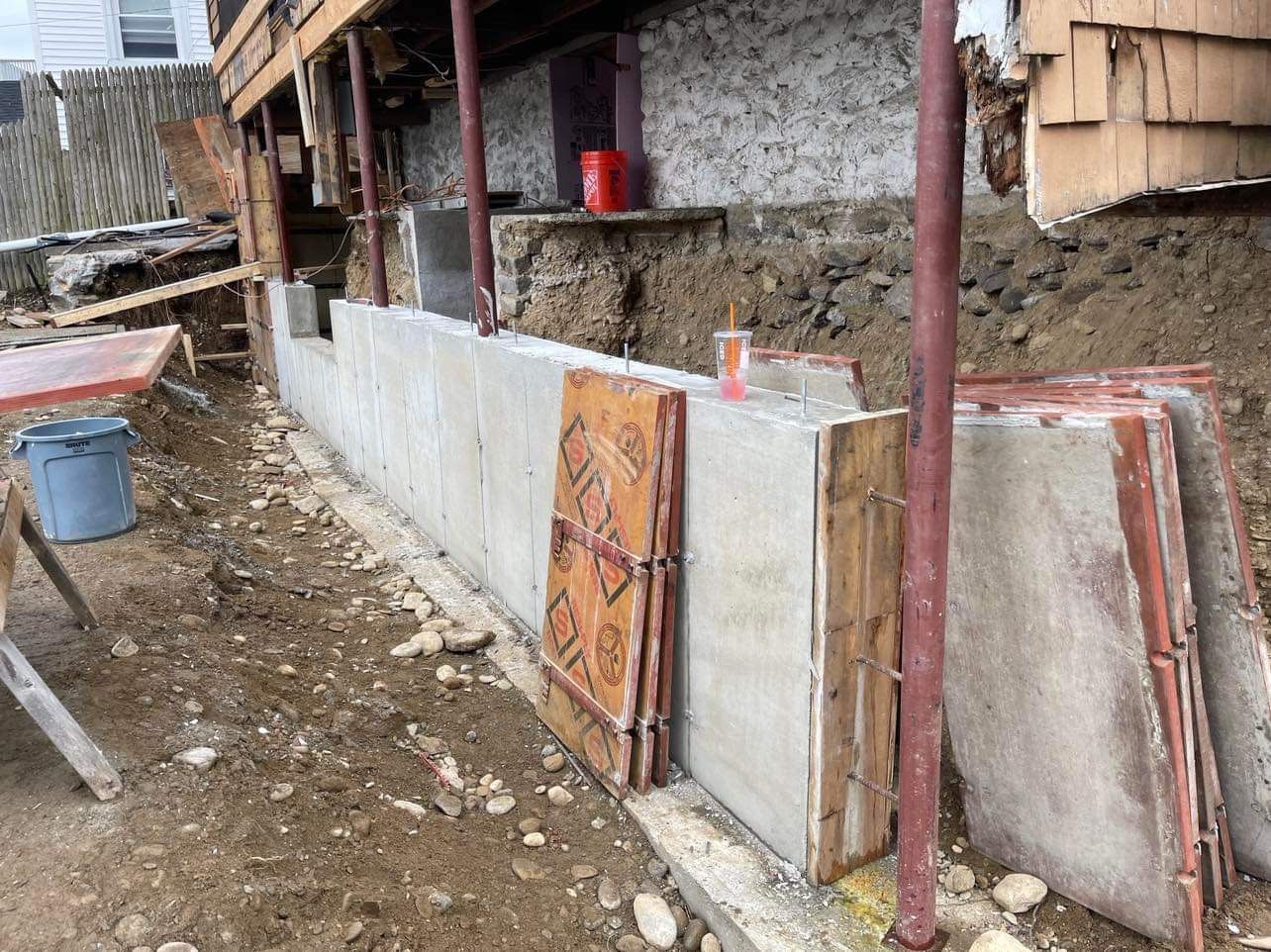Construction site: Concrete wall being built, with wooden forms and exposed soil.