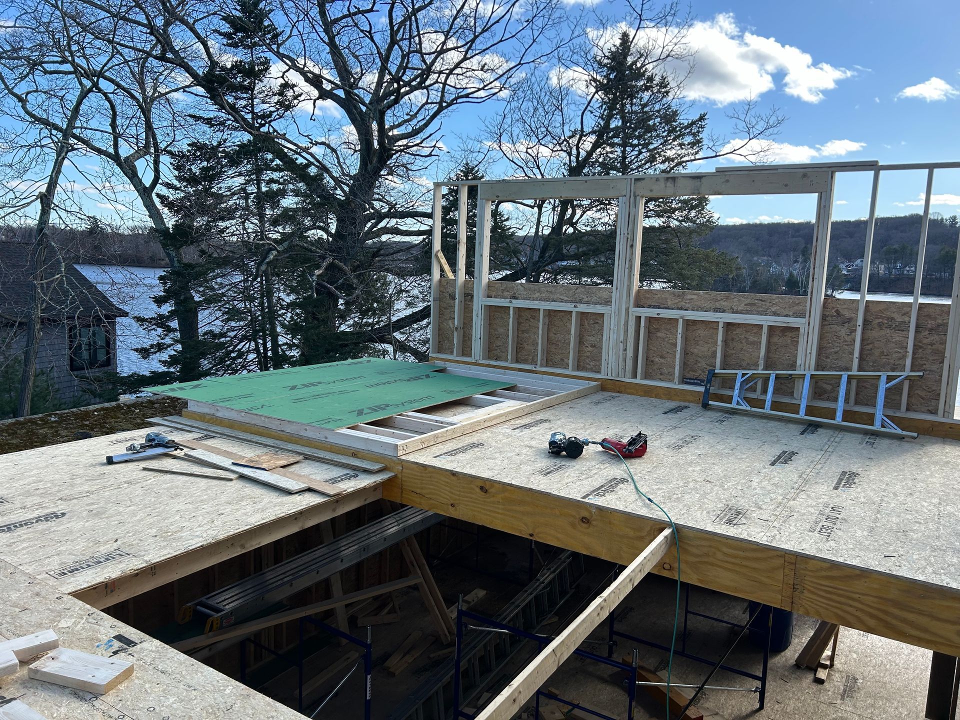 Construction site: wooden frame of a building with a lake view, partially built.