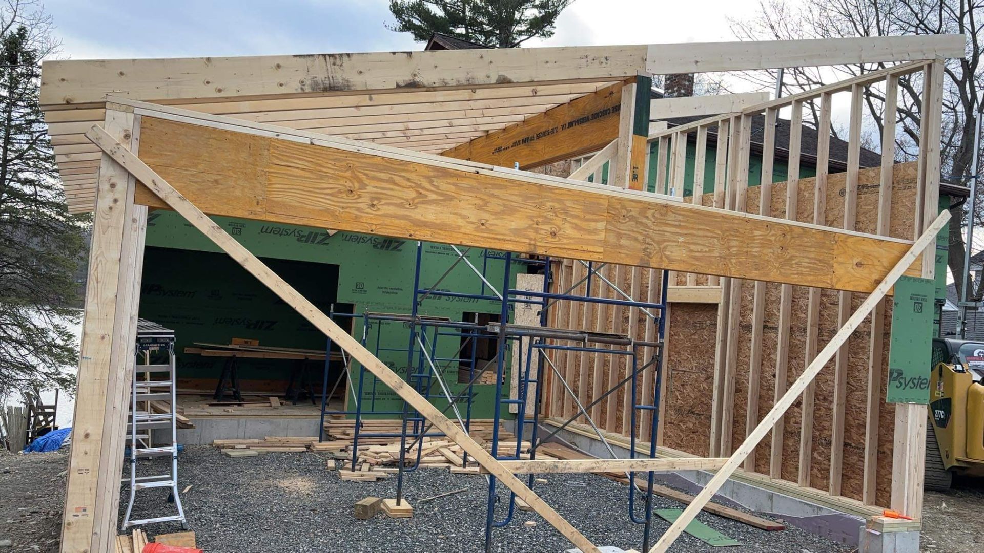 Construction of a building's roof with angled wooden supports. Framing and scaffolding are visible.