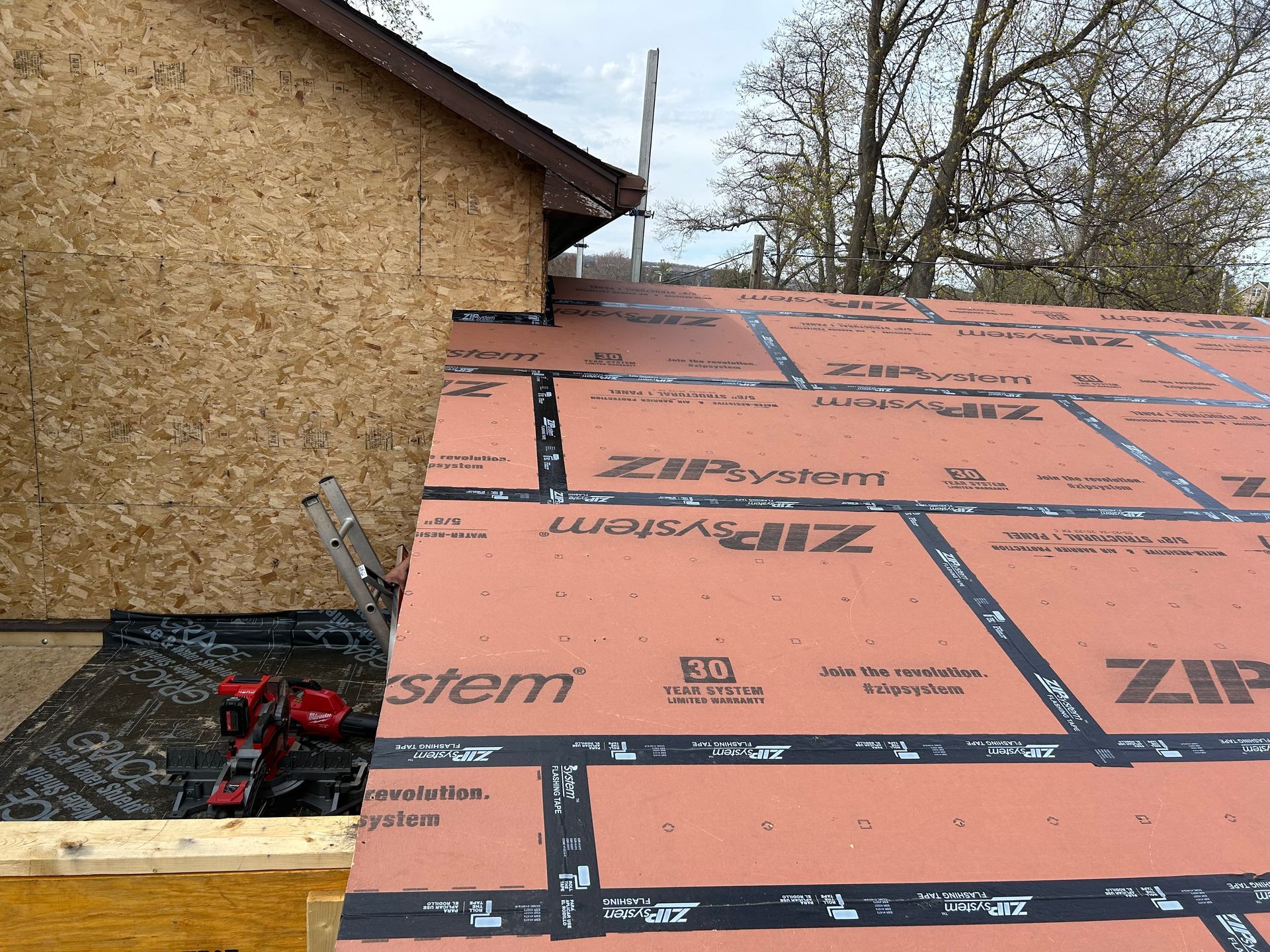 Roof construction: ZIP System sheathing with black taped seams, power tools.