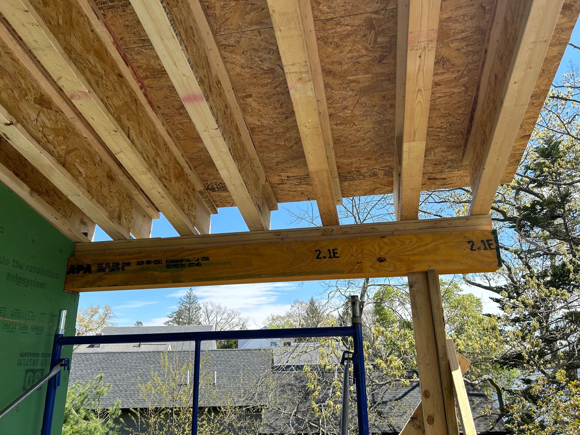 Wooden frame construction; OSB subfloor and beams; blue sky background.