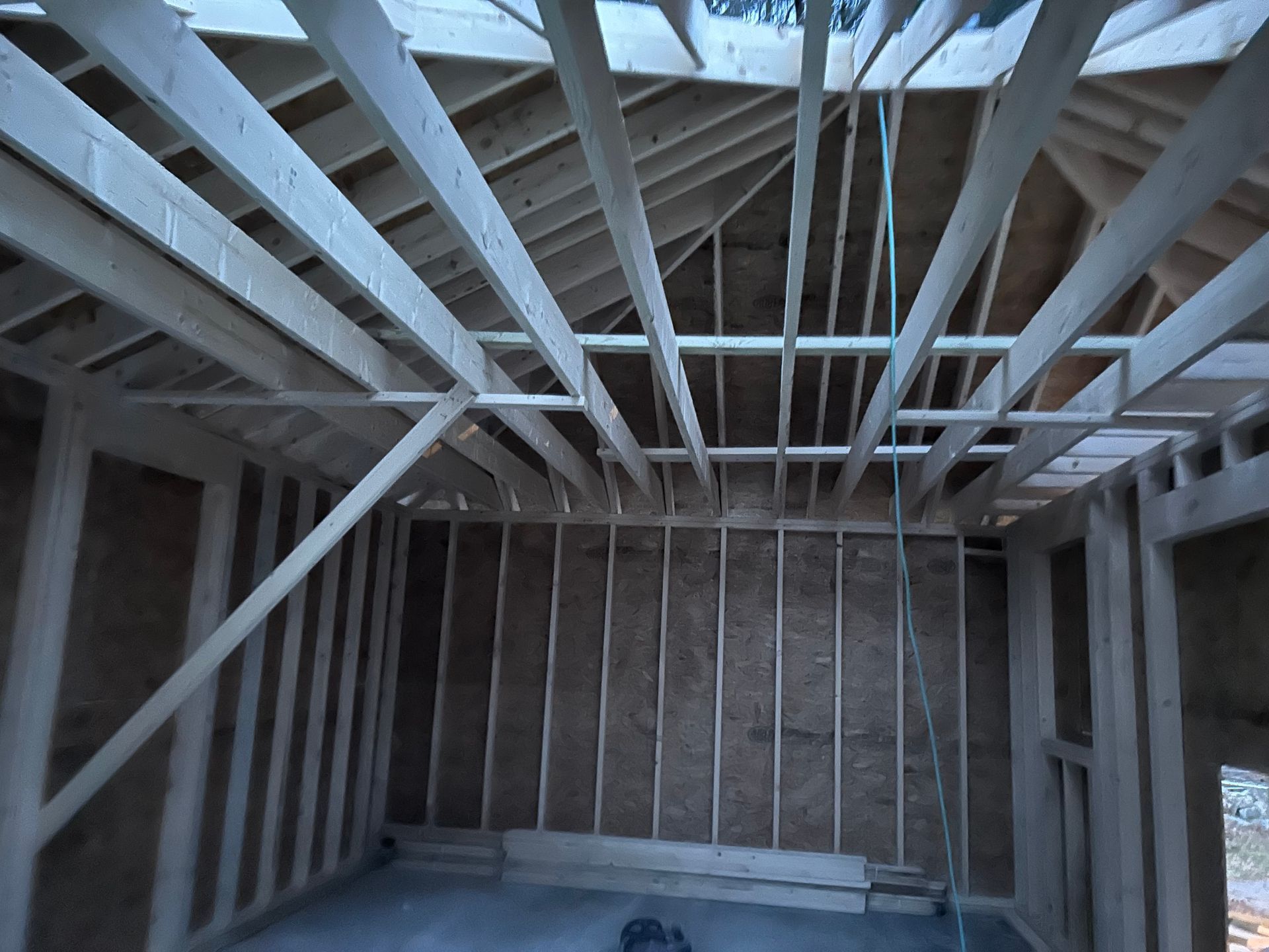 Interior view of a building under construction, showing wooden framing for walls and roof.