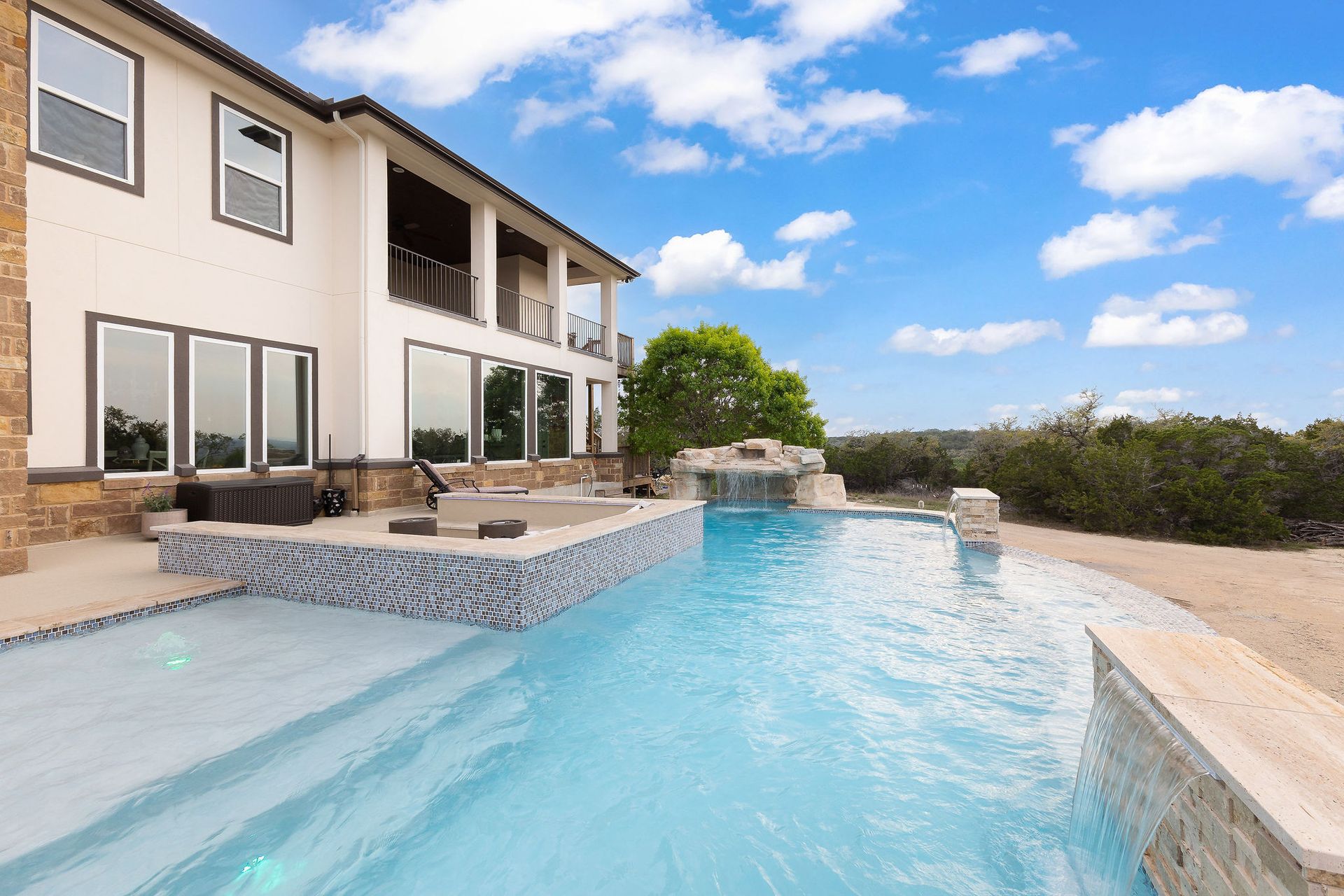 Modern two-story house with a backyard pool and patio under a blue sky