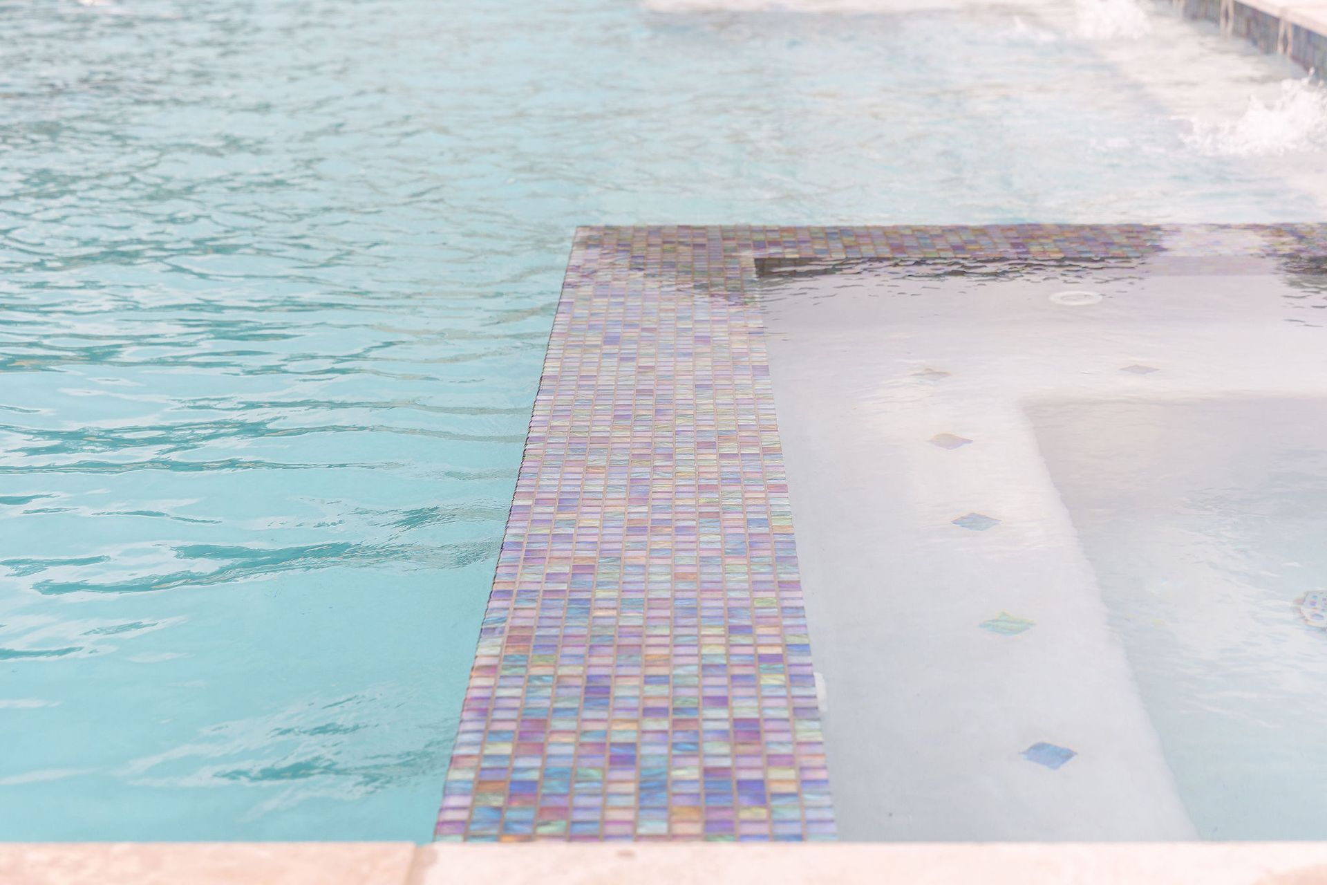 Blue swimming pool beside a tiled deck and spa area