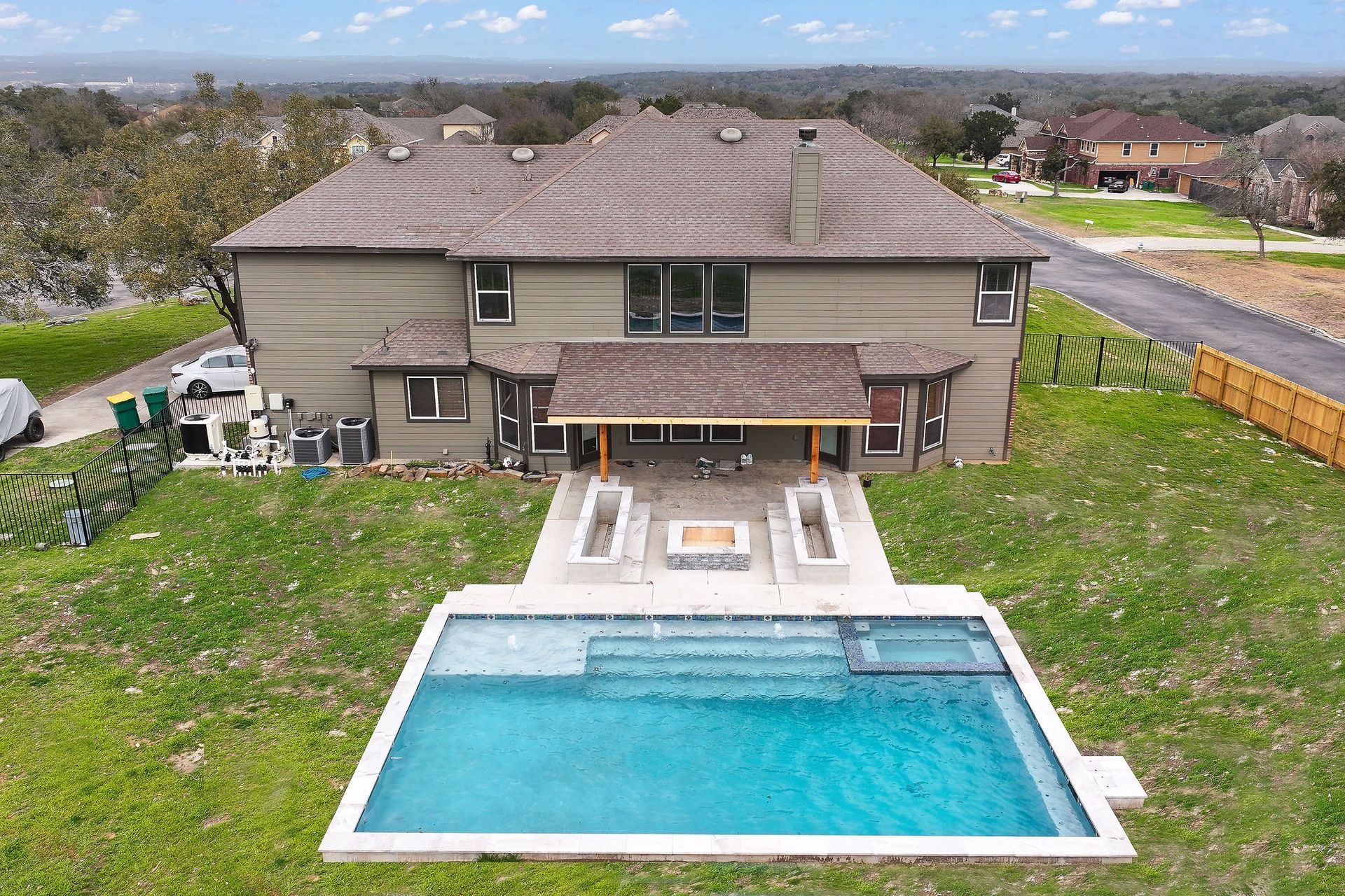 Backyard with two-story house, patio, and rectangular swimming pool with blue water