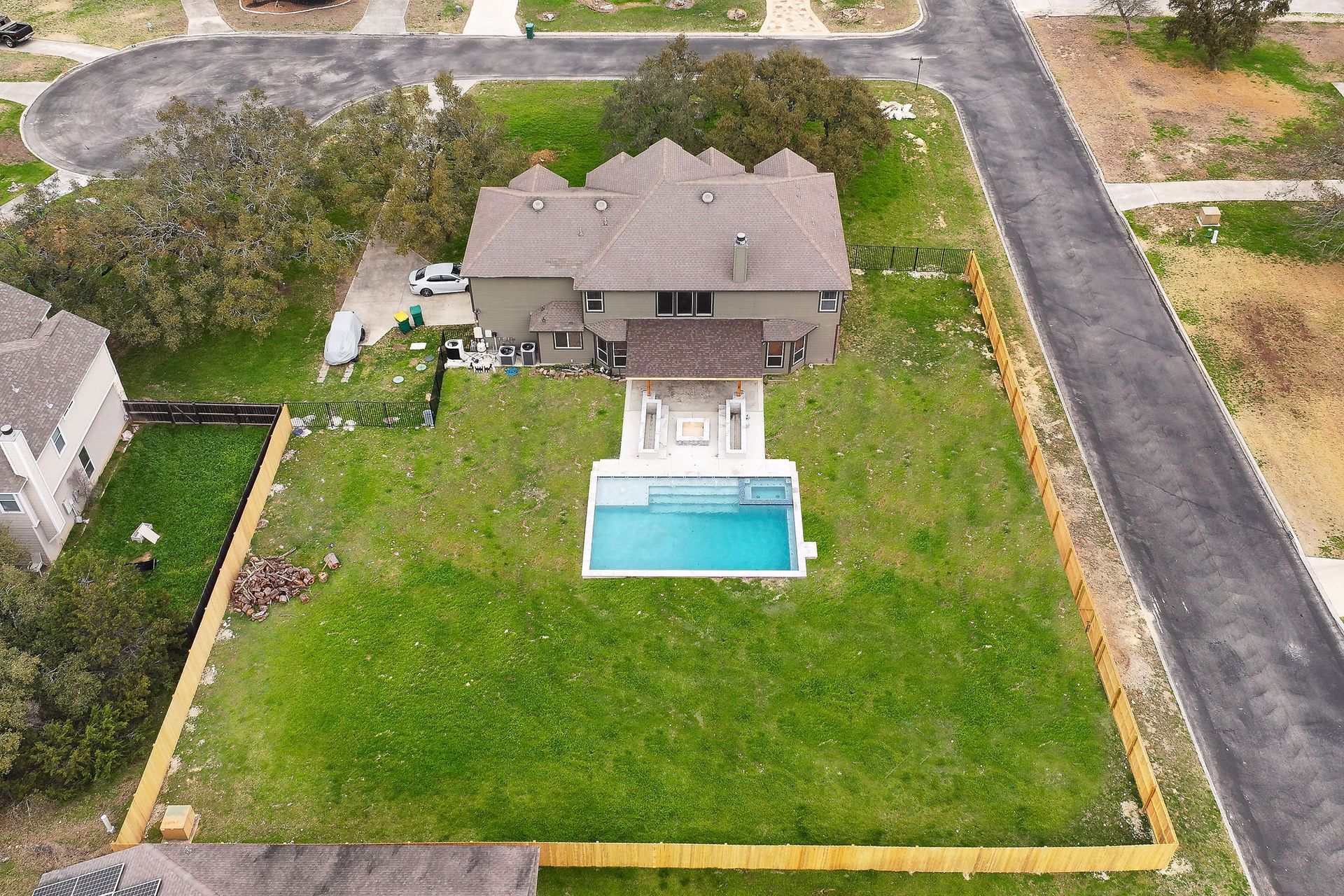 Aerial view of a suburban house with a backyard pool, patio, and large green lawn.