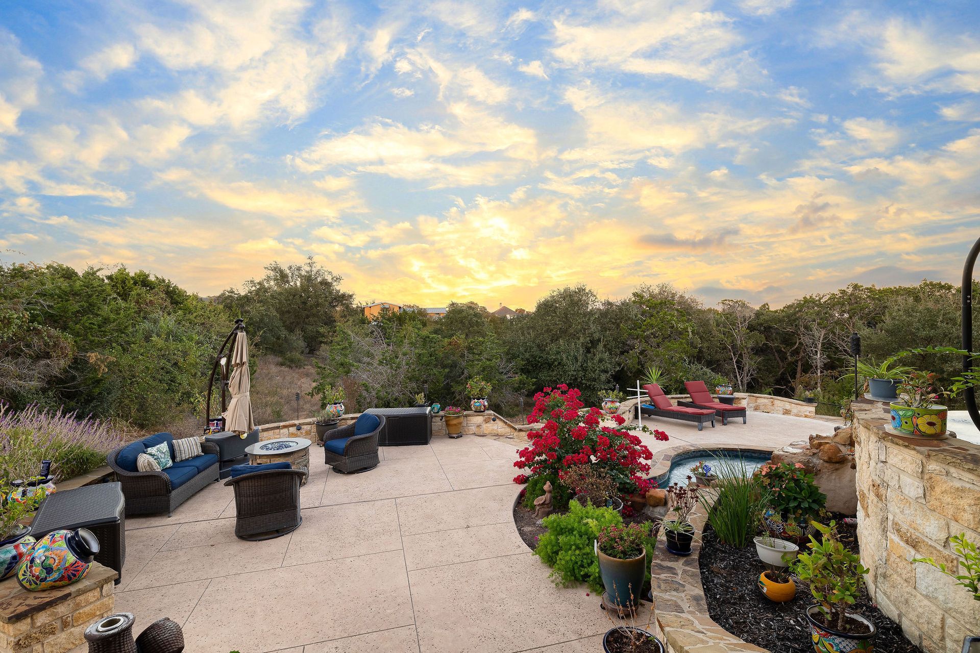 Backyard pool at sunset with chairs, potted plants, and a cloudy sky