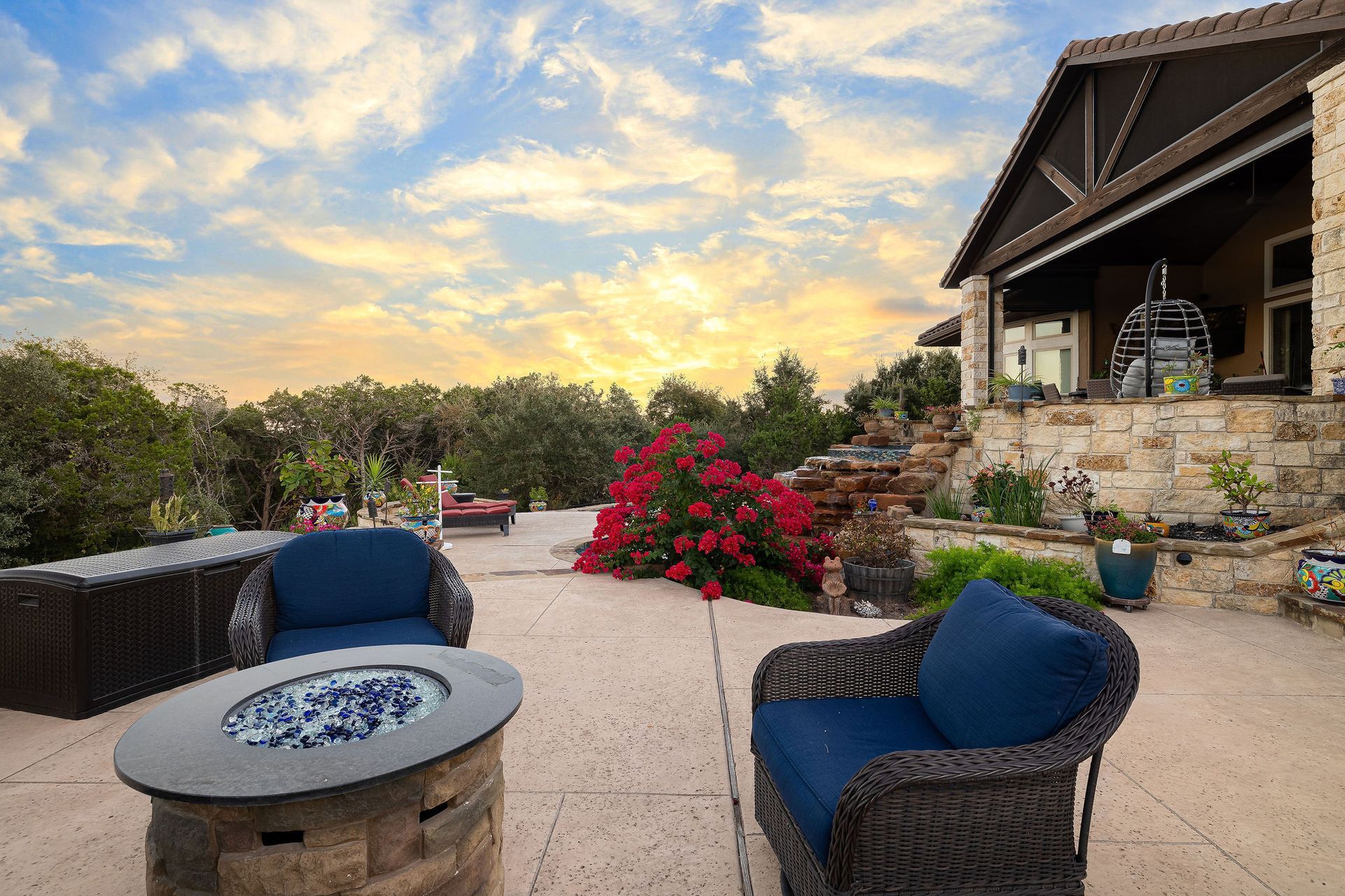 Backyard pool at sunset with chairs, potted plants, and a cloudy sky