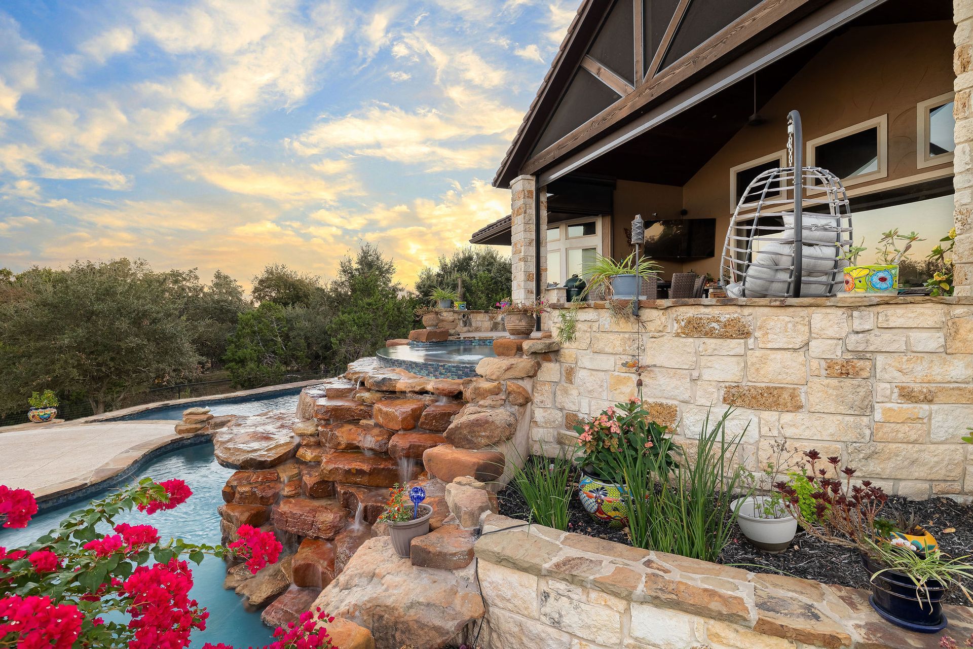 Backyard pool at sunset with chairs, potted plants, and a cloudy sky