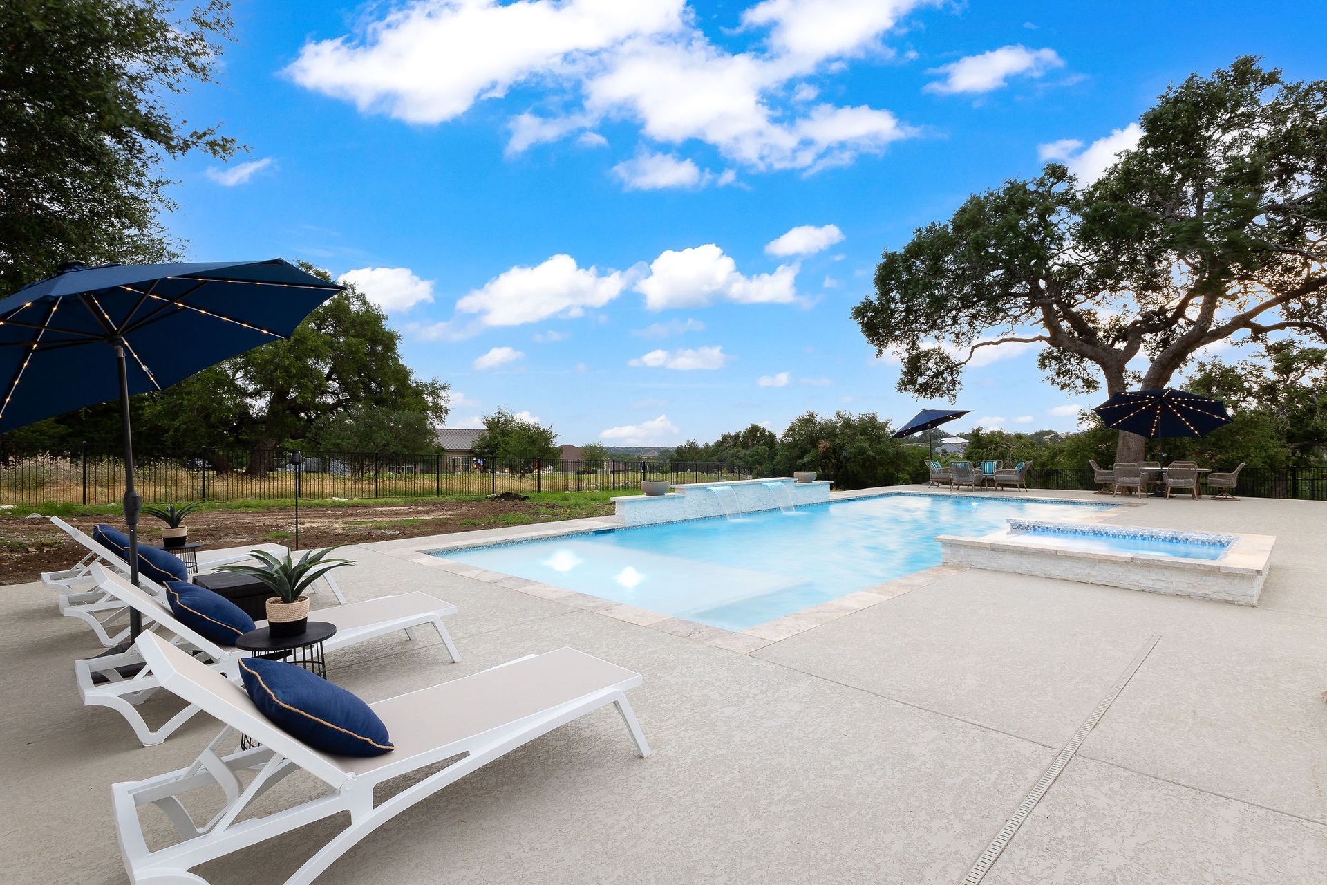 Modern outdoor swimming pool with blue water and a tiled waterfall feature