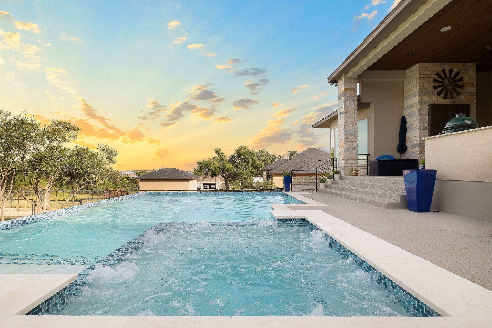Modern backyard pool at sunset with patio seating and a house beside it