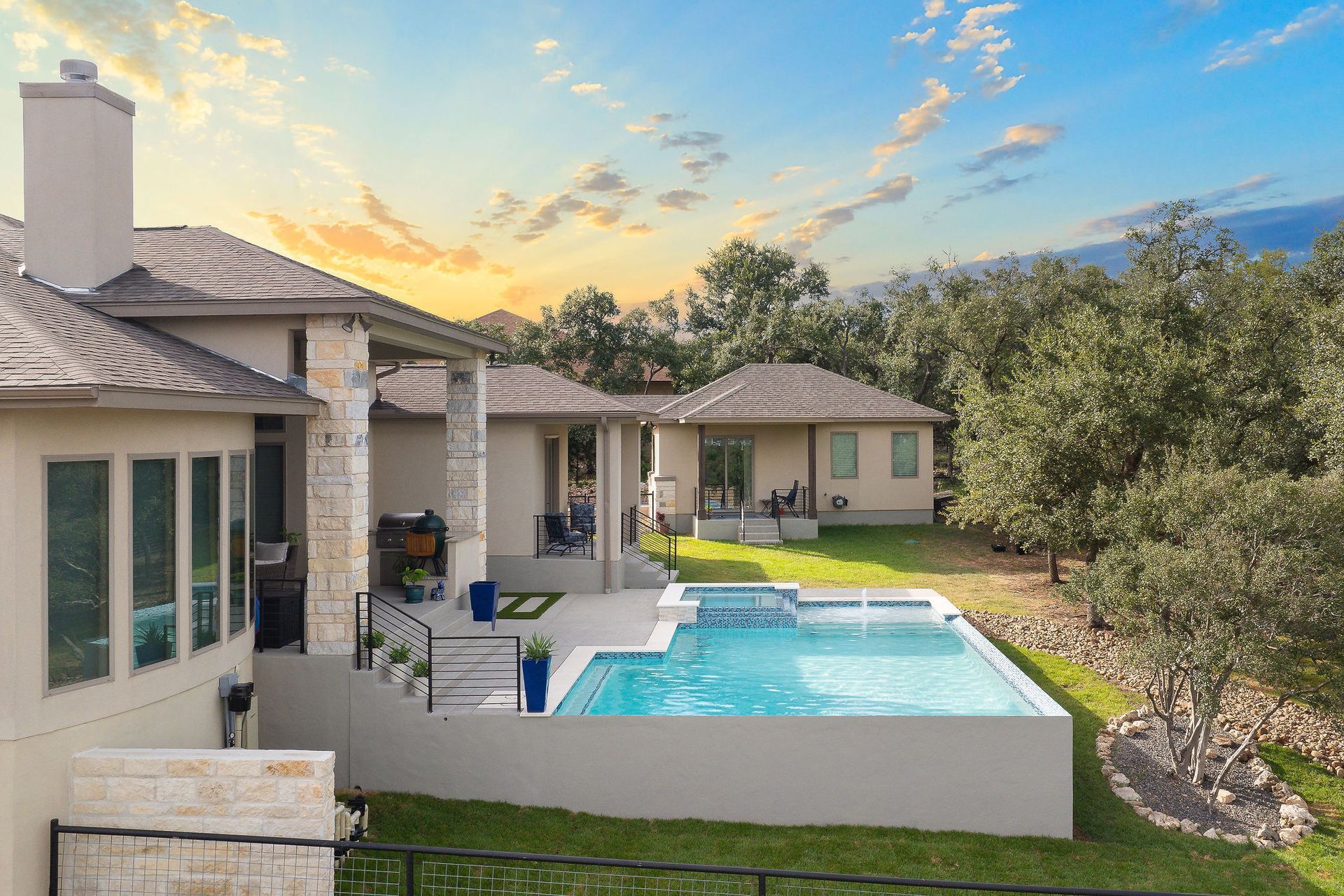 Backyard patio with a swimming pool beside a beige house at sunset