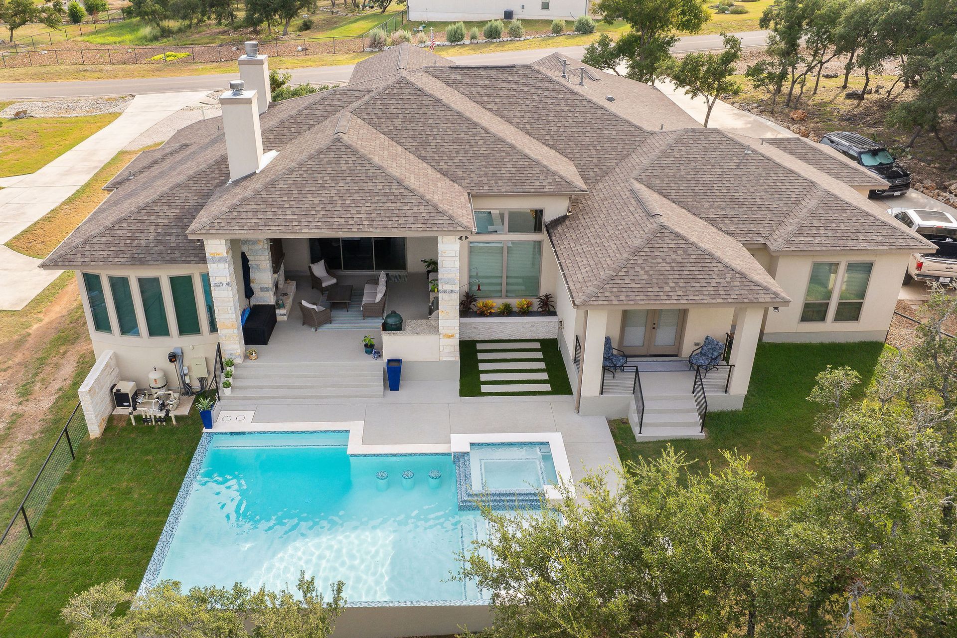 Aerial view of a luxury house with a backyard pool, patio, and landscaped yard.