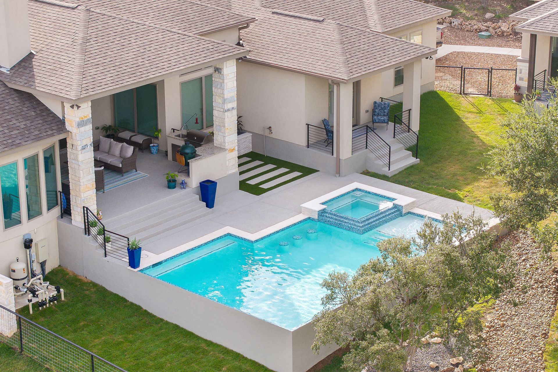 Modern white villa patio with turquoise pool, hot tub, lounge chairs, and sliding glass doors