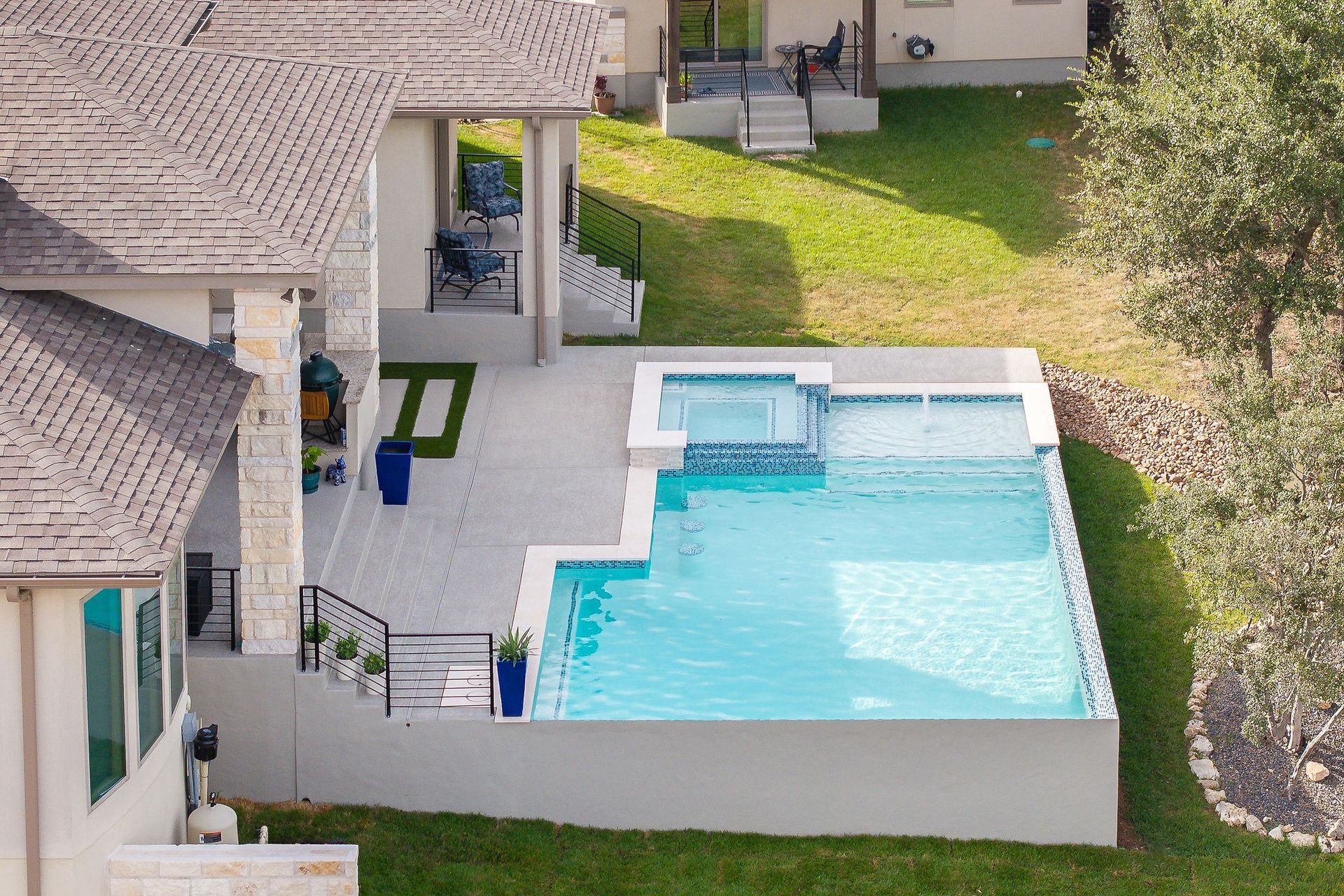 Aerial view of a modern backyard with a rectangular swimming pool and patio beside a house