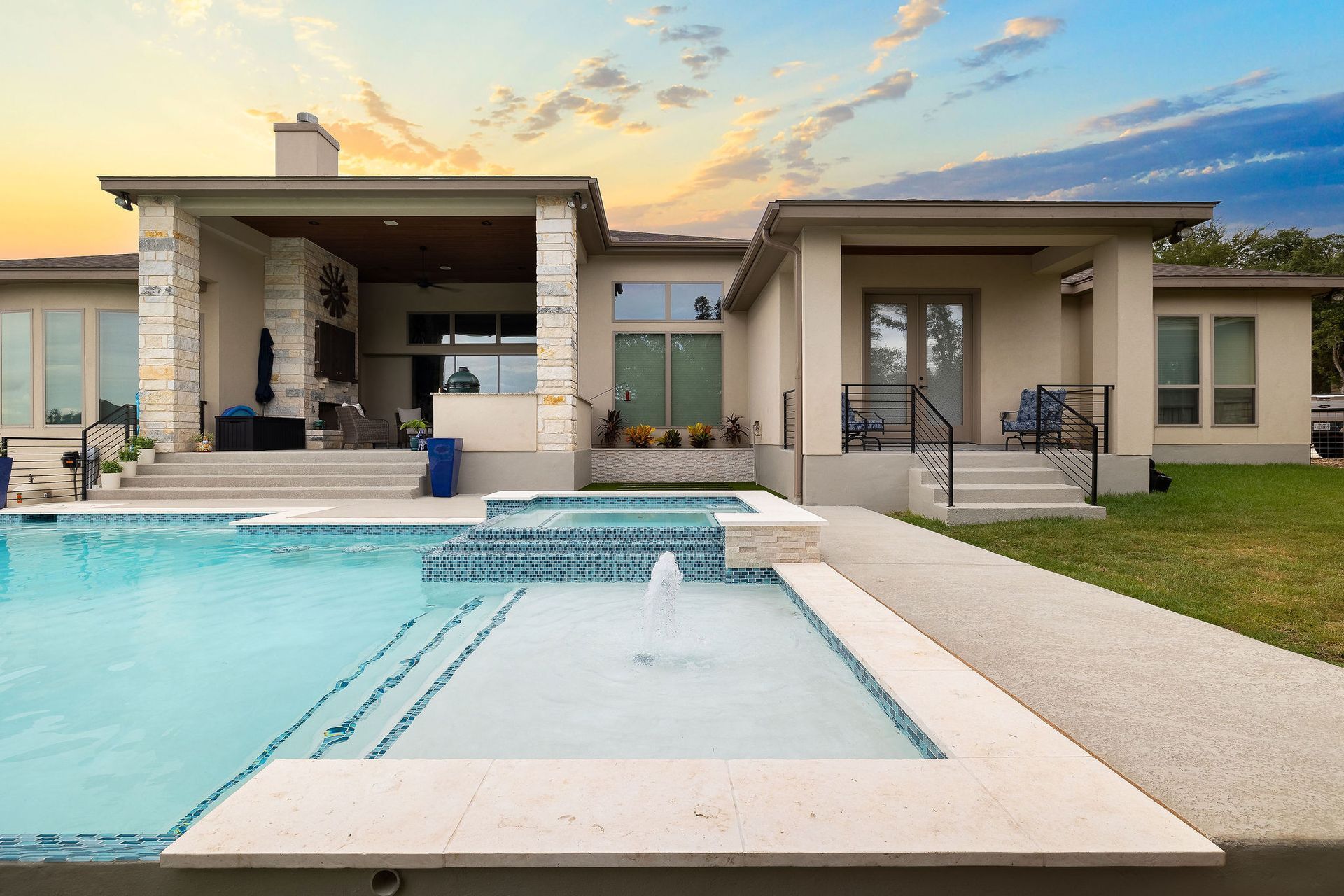 Modern house with a backyard swimming pool and covered patio at sunset