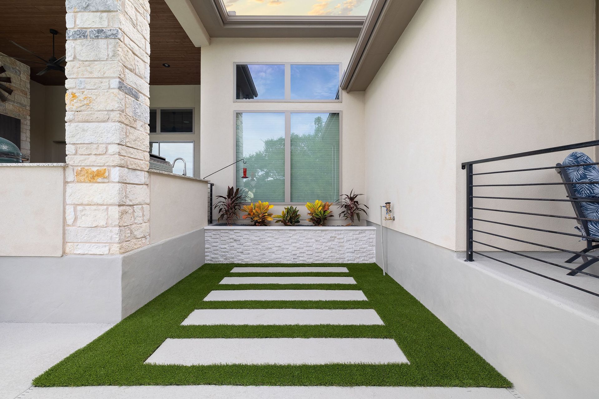 Front porch with artificial grass stepping stones leading to a glass front door.