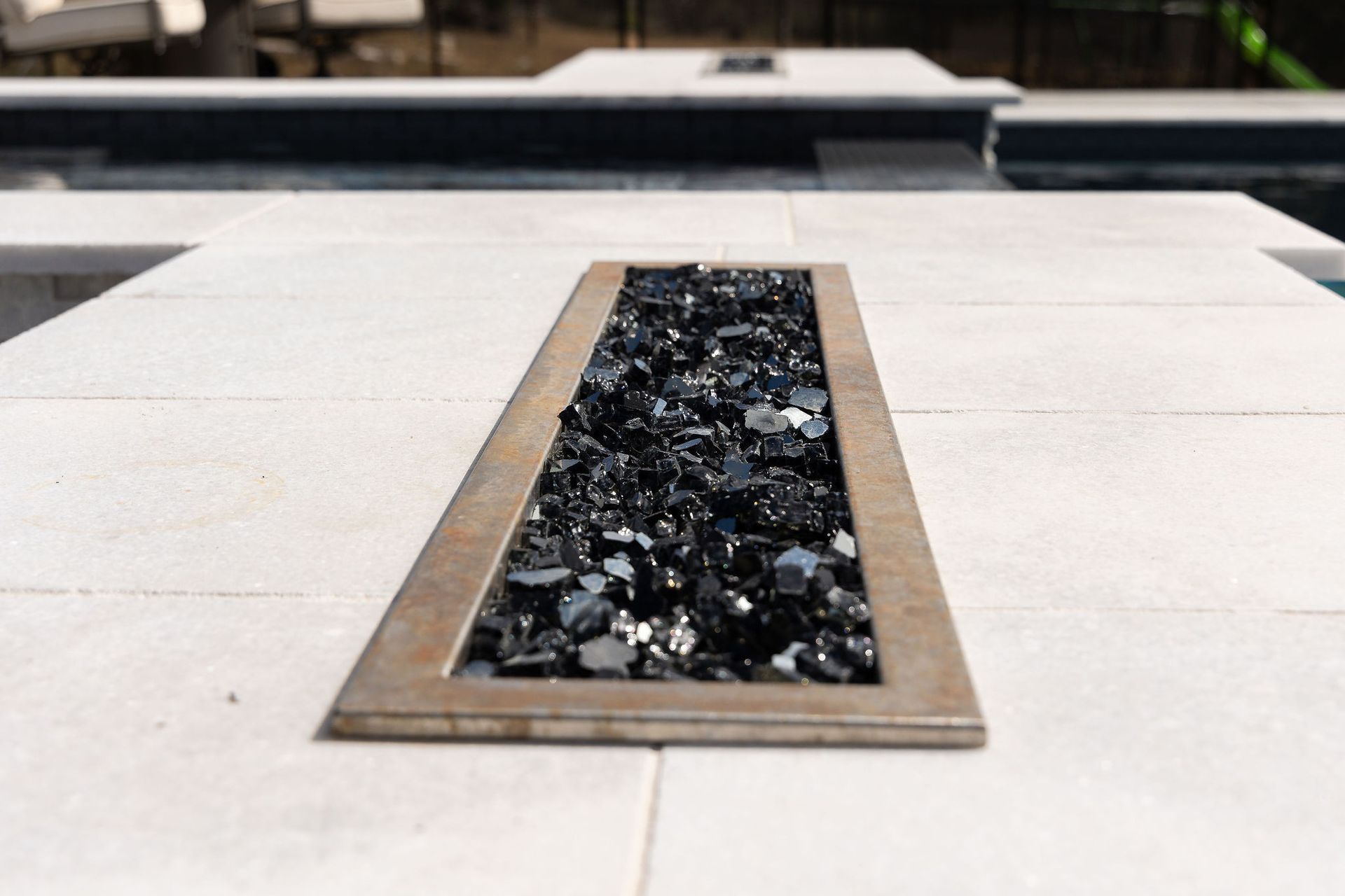 Rectangular recessed planter with dark stones set into a light stone walkway