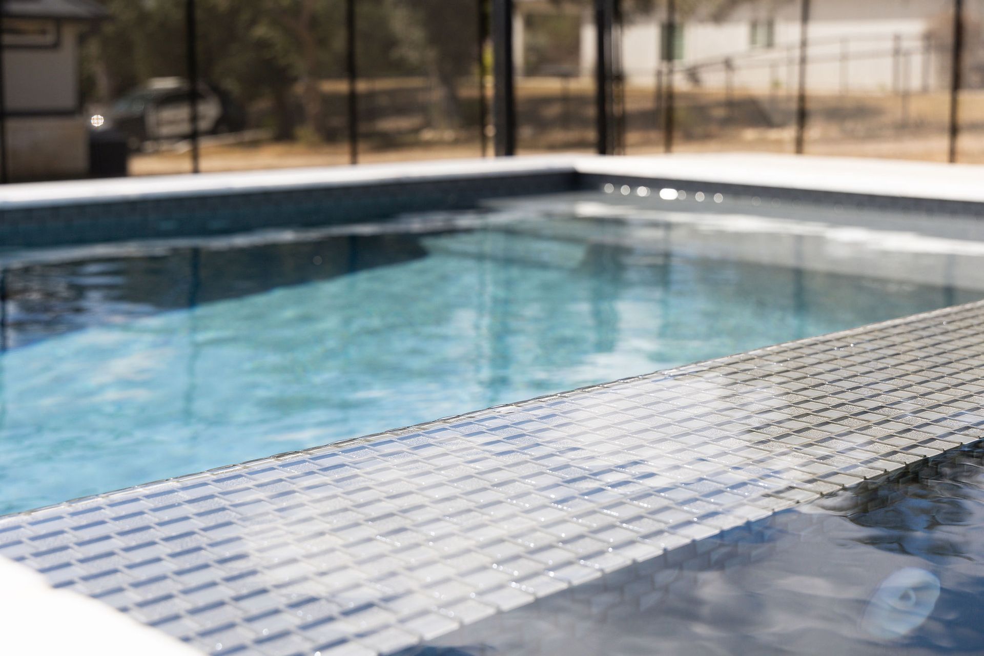 Swimming pool with a tiled edge and clear blue water, outdoors in a sunny setting