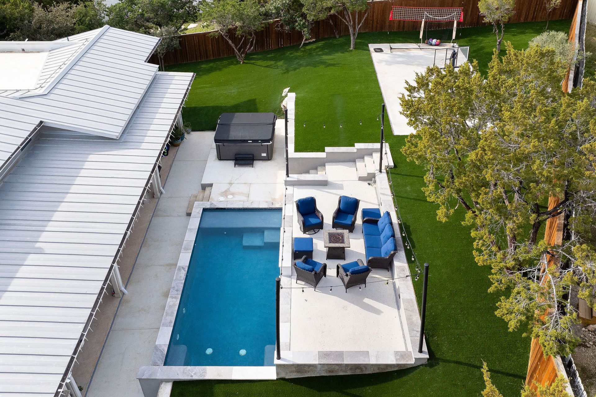Backyard patio with pool, white deck, blue lounge chairs, grill, and green lawn