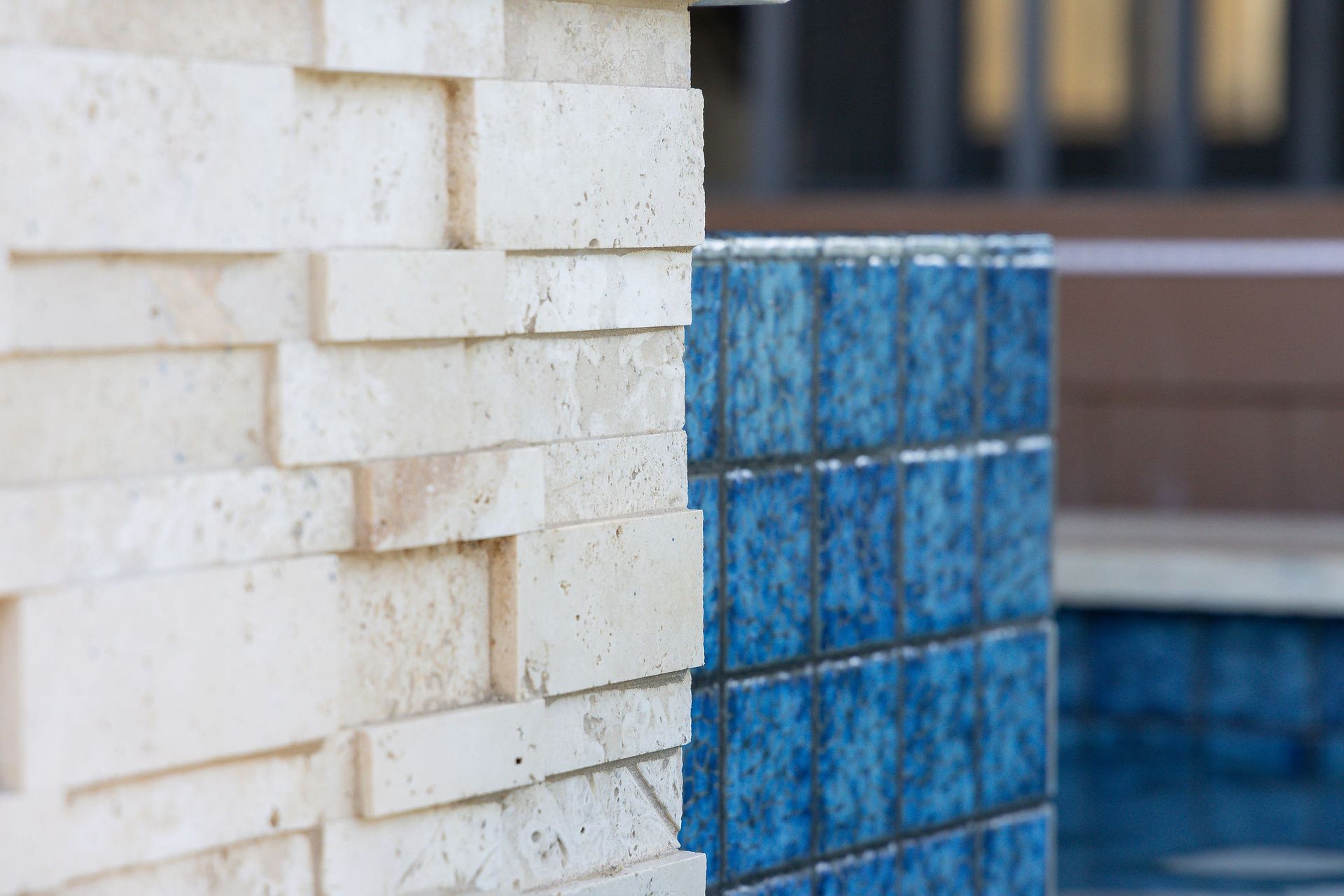 Close-up of white bricks beside a blue tiled wall with water in the background
