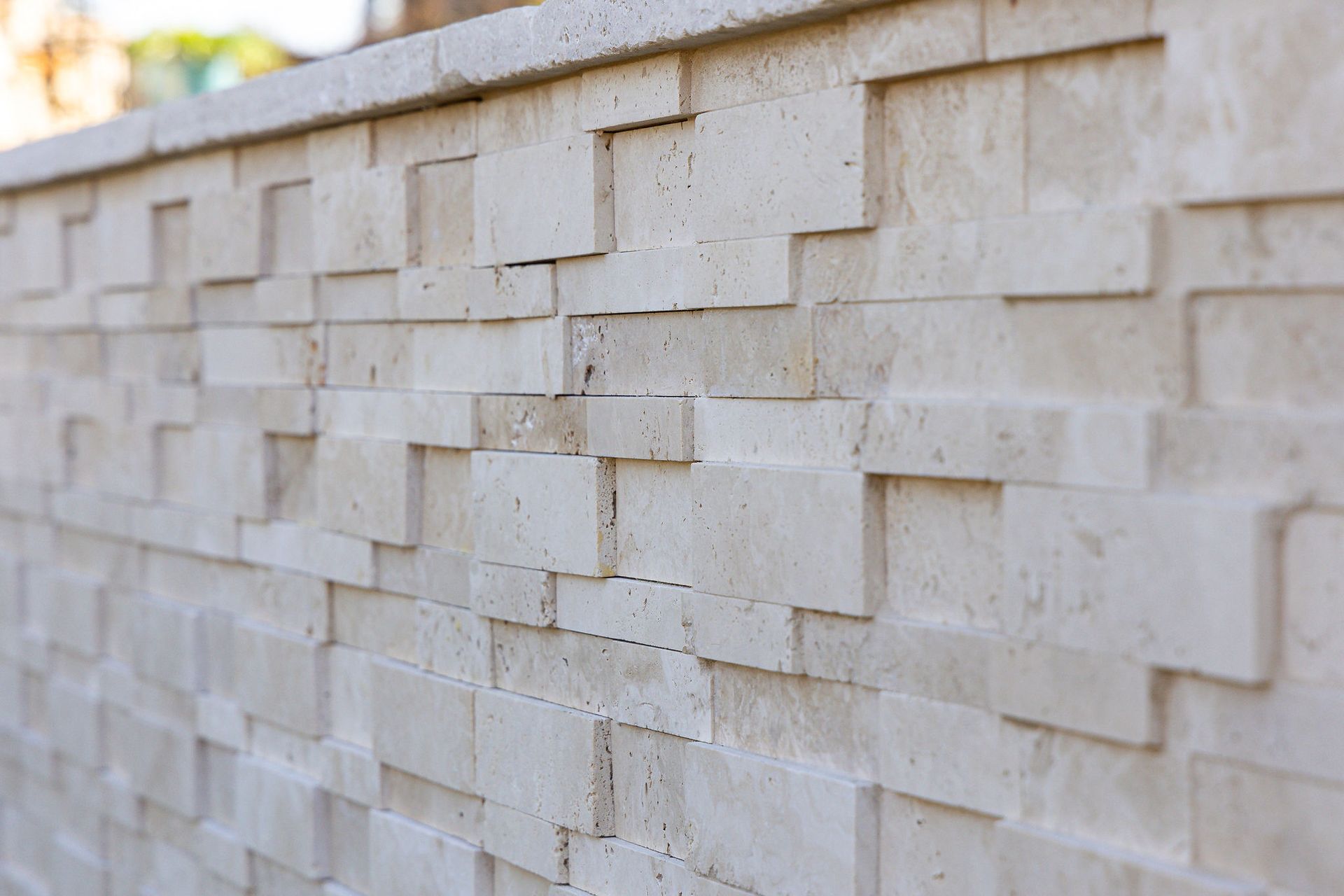 Cream-colored stone wall with staggered rectangular blocks and a light capstone along the top