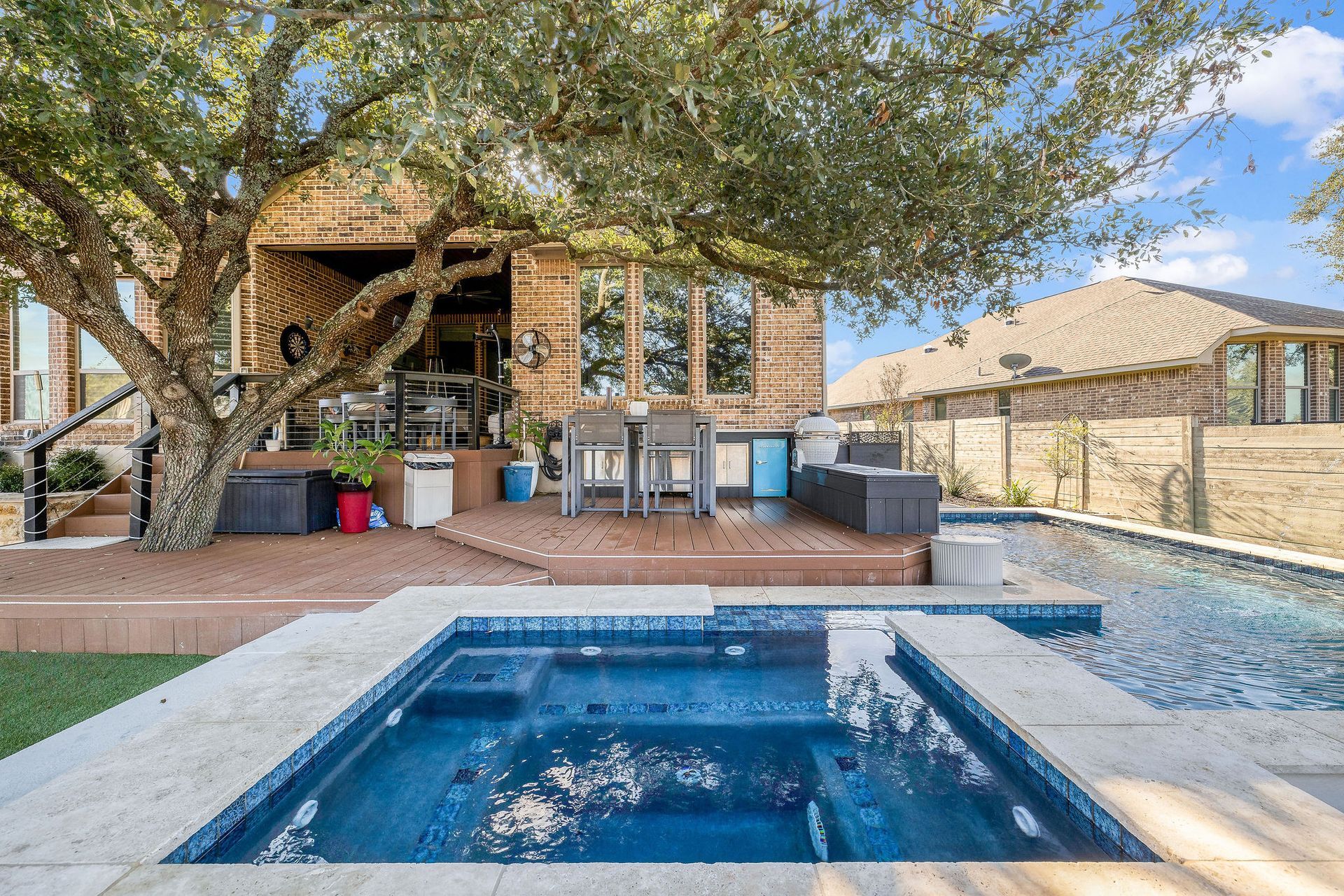Backyard patio with a small blue pool, brick house, trees, and desert landscaping
