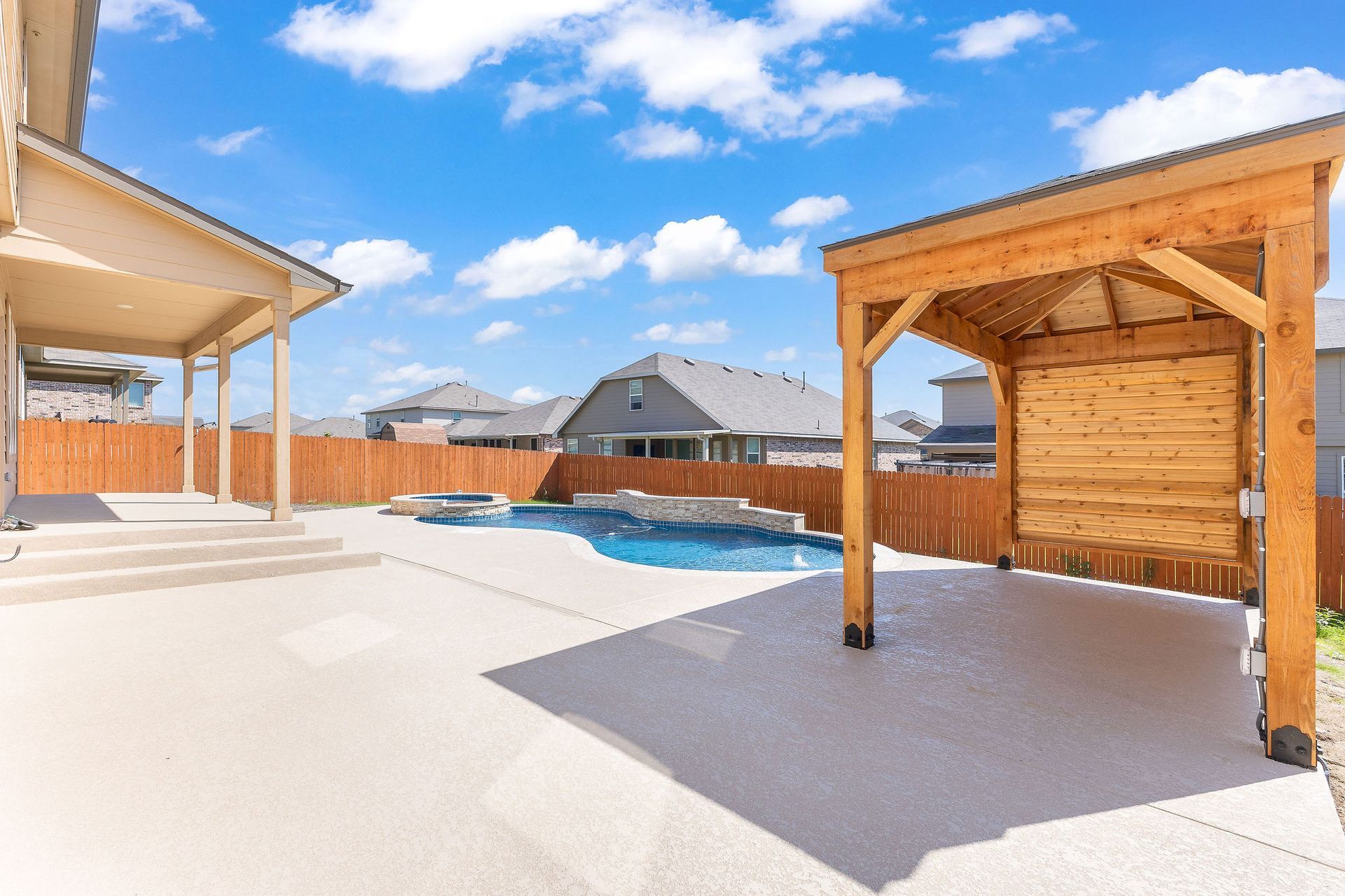Modern backyard with a turquoise pool, lounge chairs, trees, and a sunset sky over hills.