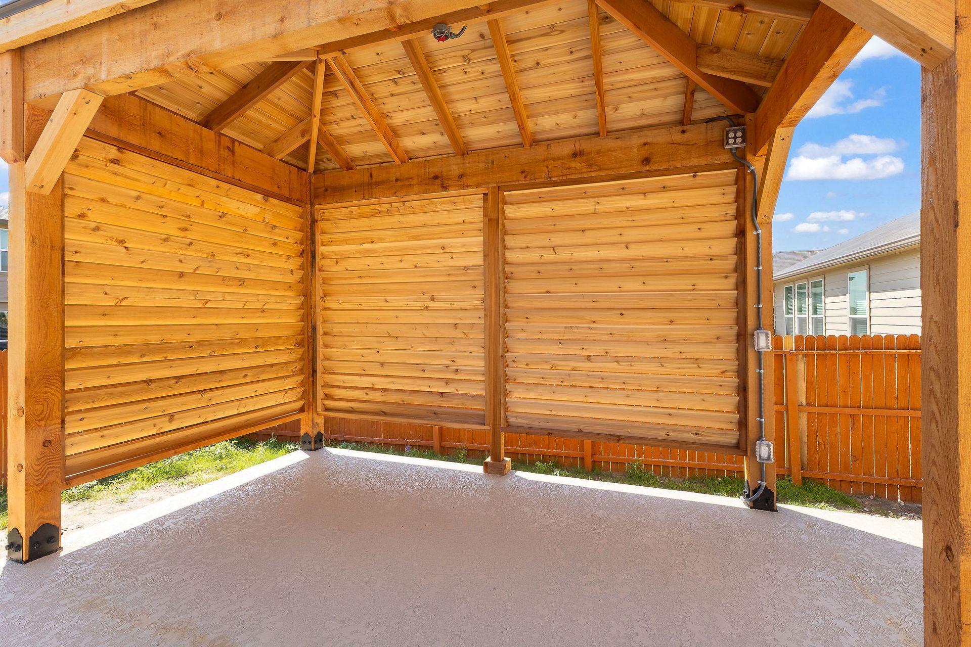 Modern backyard with a turquoise pool, lounge chairs, trees, and a sunset sky over hills.