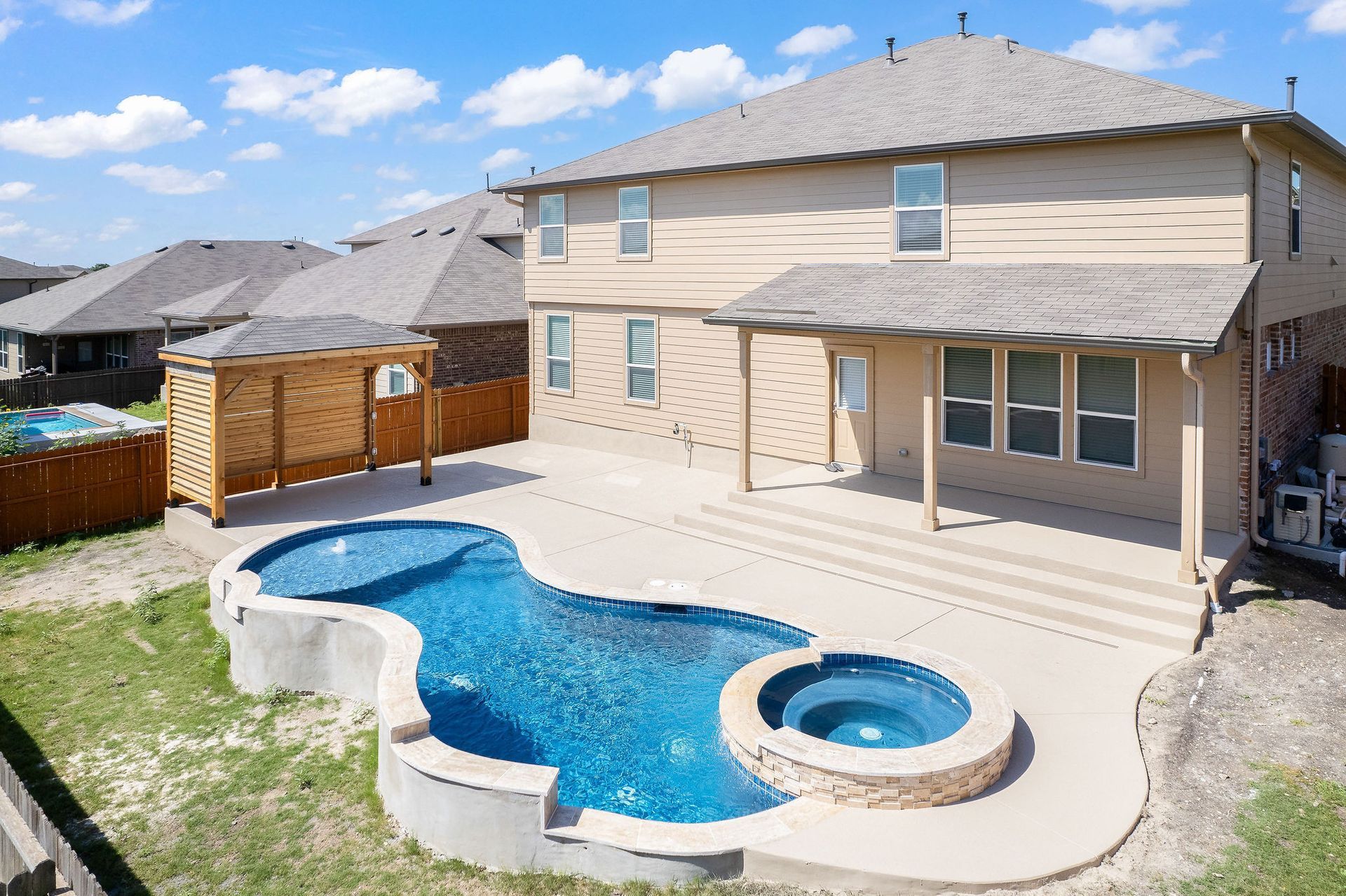 Modern backyard with a turquoise pool, lounge chairs, trees, and a sunset sky over hills.