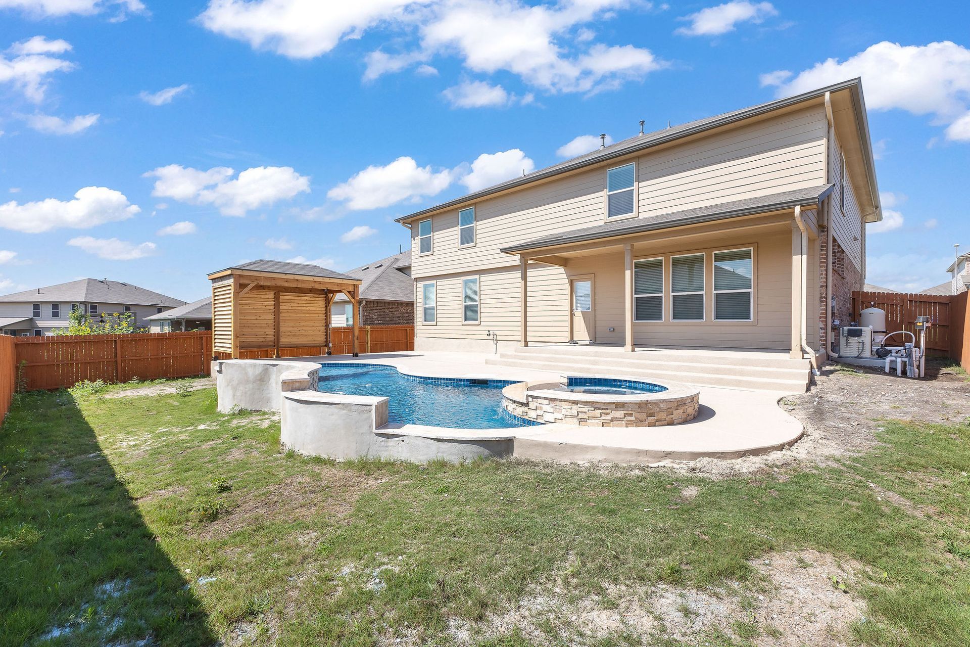 Modern backyard with a turquoise pool, lounge chairs, trees, and a sunset sky over hills.
