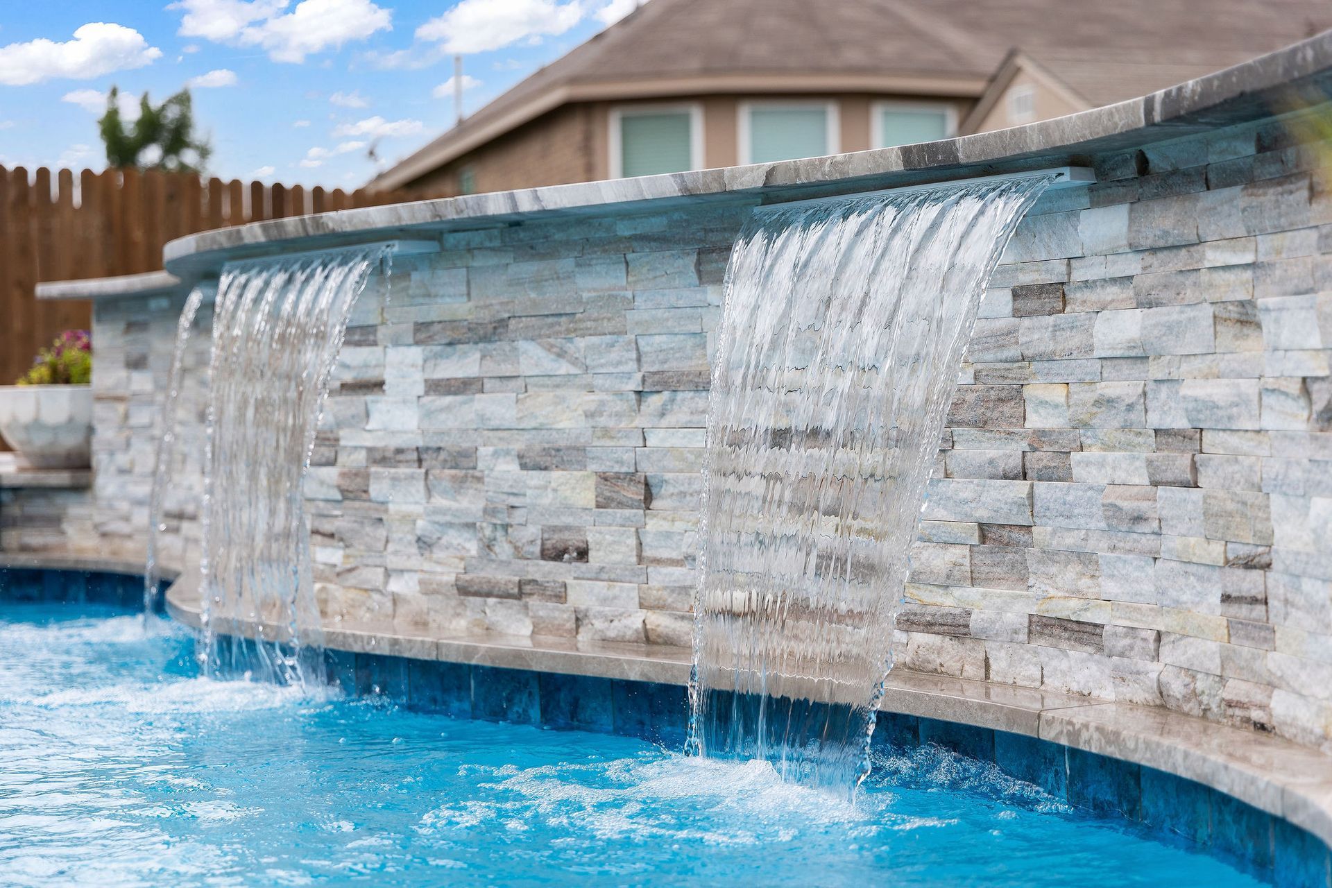 Backyard pool with spa, patio lounge chairs, and desert-style homes under a bright blue sky