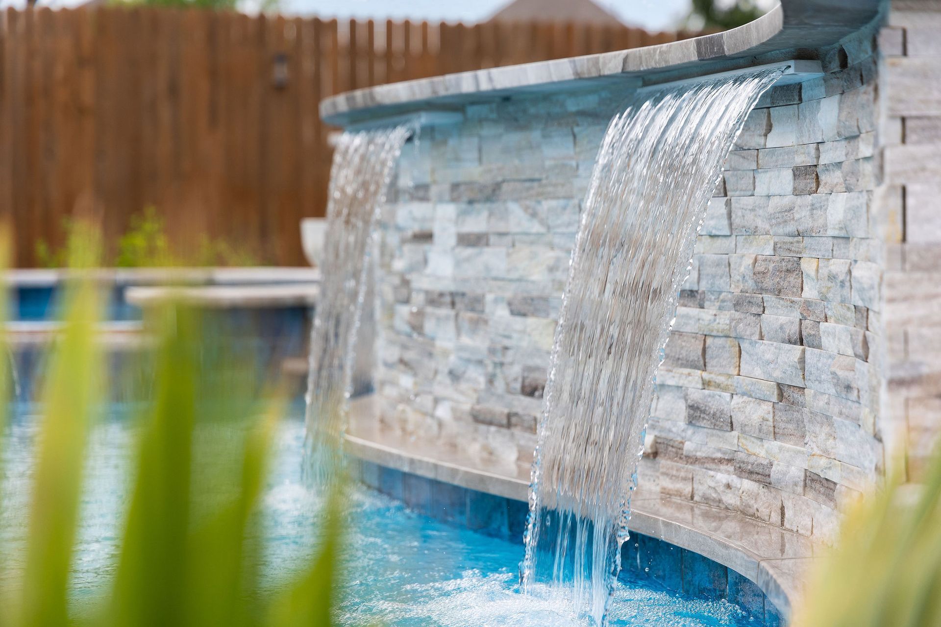 Backyard pool with spa, patio lounge chairs, and desert-style homes under a bright blue sky