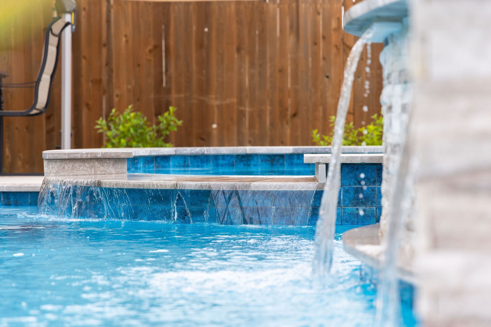 Backyard pool with spa, patio lounge chairs, and desert-style homes under a bright blue sky