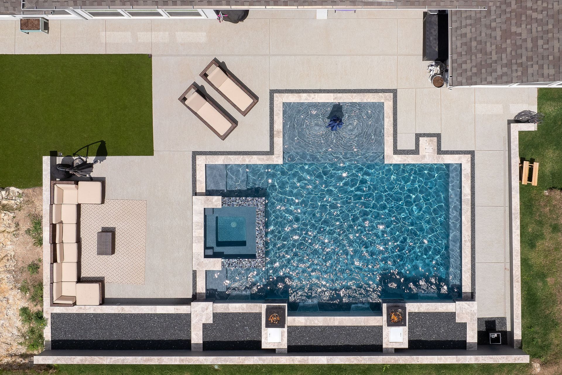 Top-down view of a modern backyard pool with tan lounge chairs and a small square hot tub