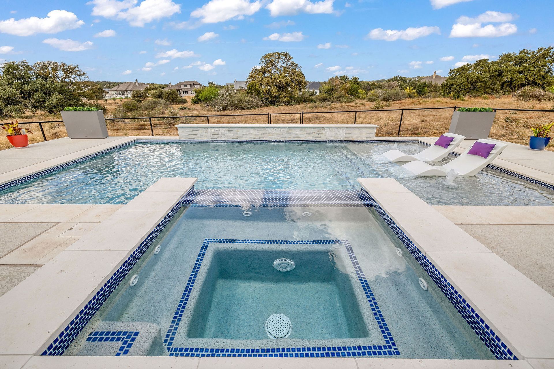 Backyard pool beside a beige house with a covered patio and desert landscaping