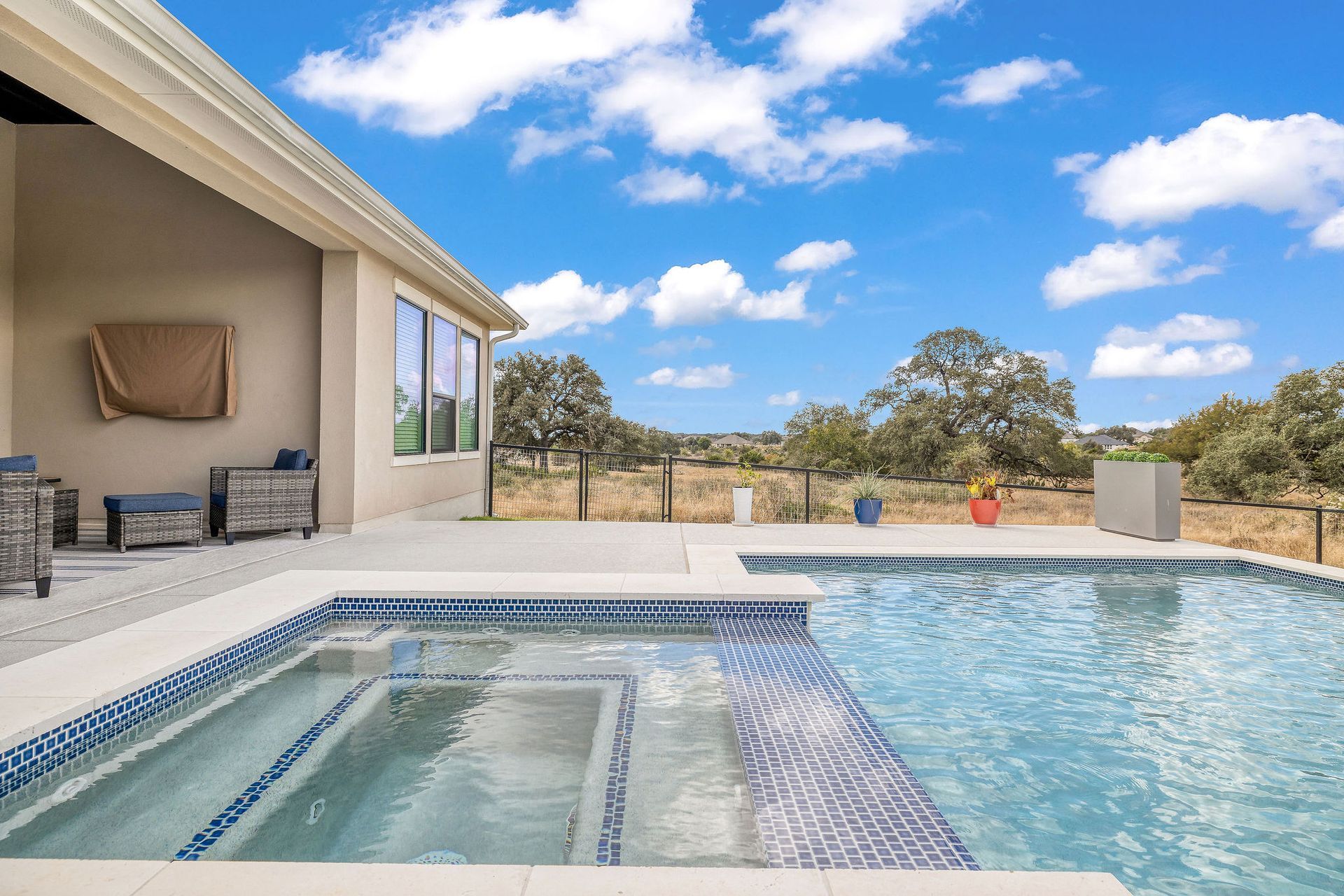 Modern patio with a blue pool, lounge chairs, and open sky view