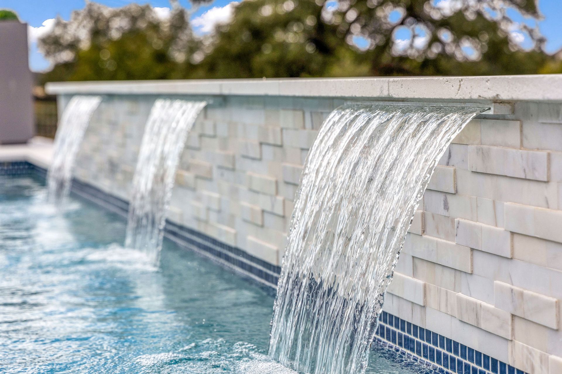 Water cascading from three spouts into a blue tiled pool